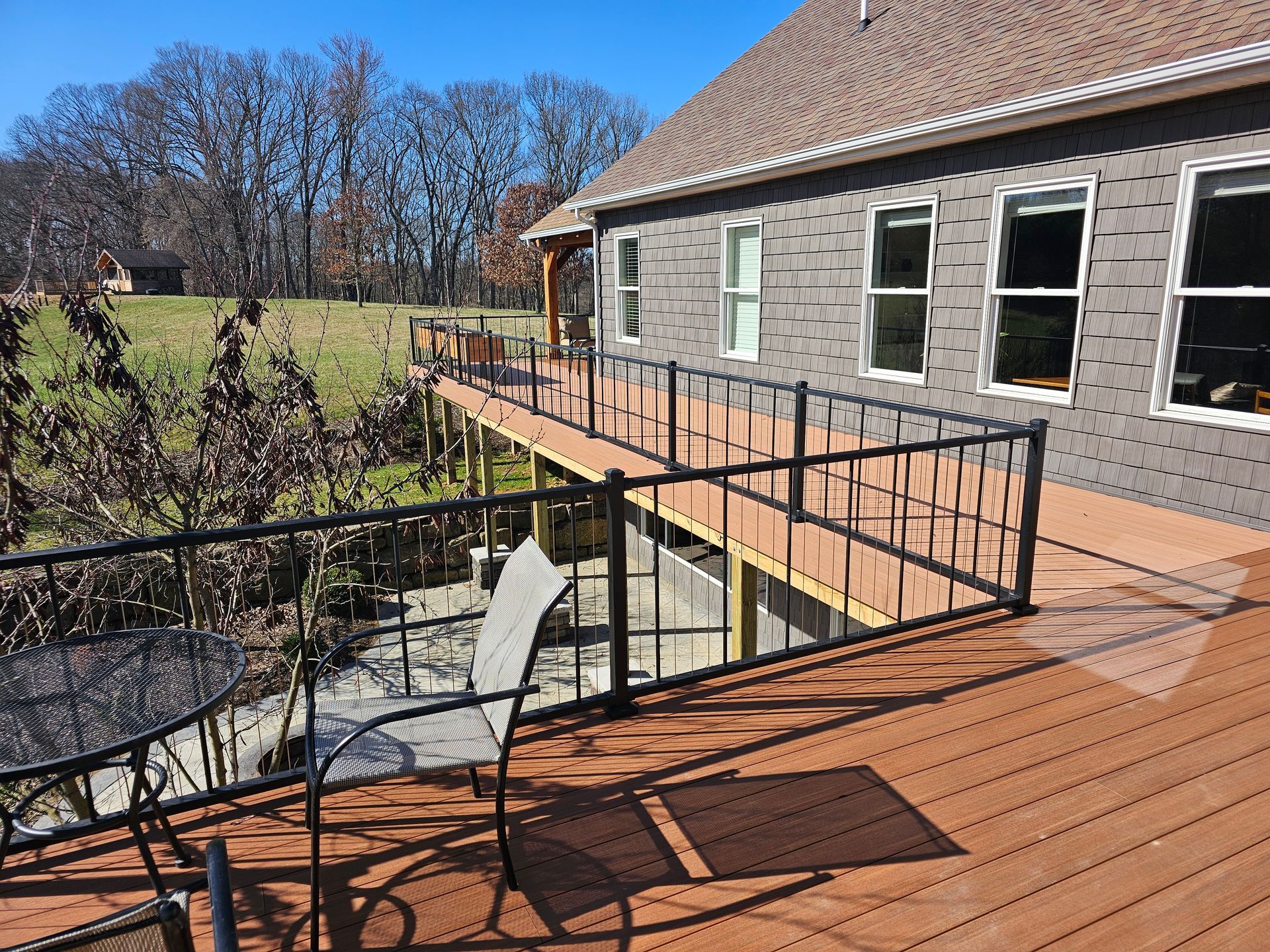 A wooden deck with a rail fence overlooking a mountainous landscape under a blue sky with clouds.