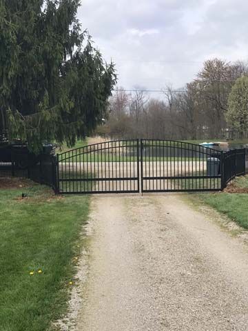 Black metal gate latch mechanism mounted on dark stained wood double doors.