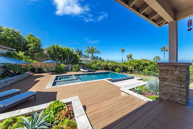A section of a tall, modern cedar wood privacy fence with vertical panels and square posts, bordering a green lawn.