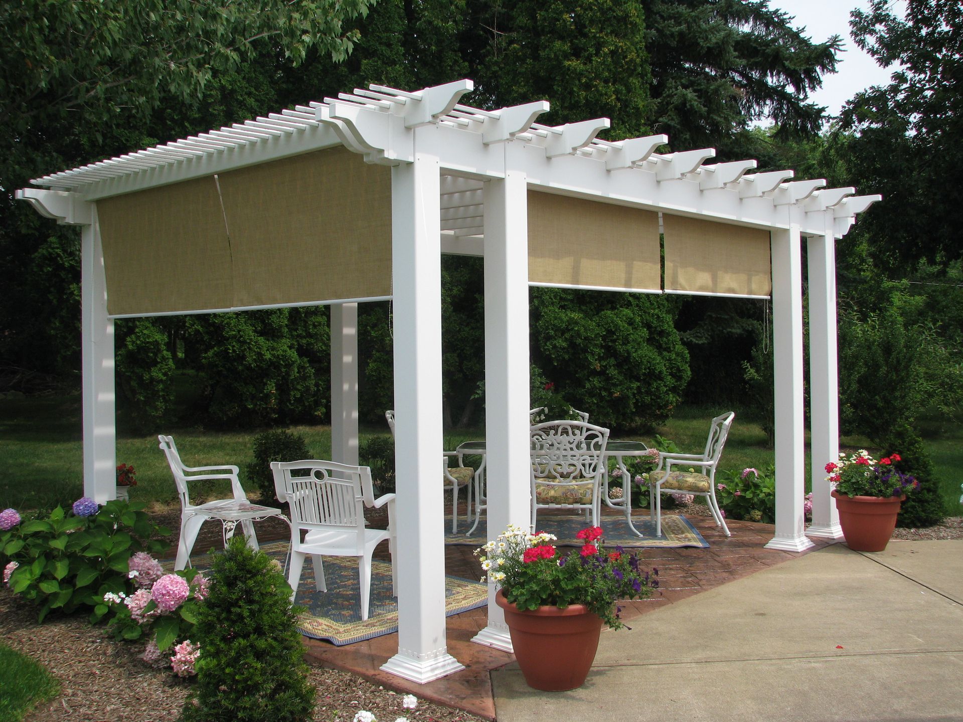 An outdoor seating area with a sectional sofa and coffee table under a wooden pergola with integrated lighting.