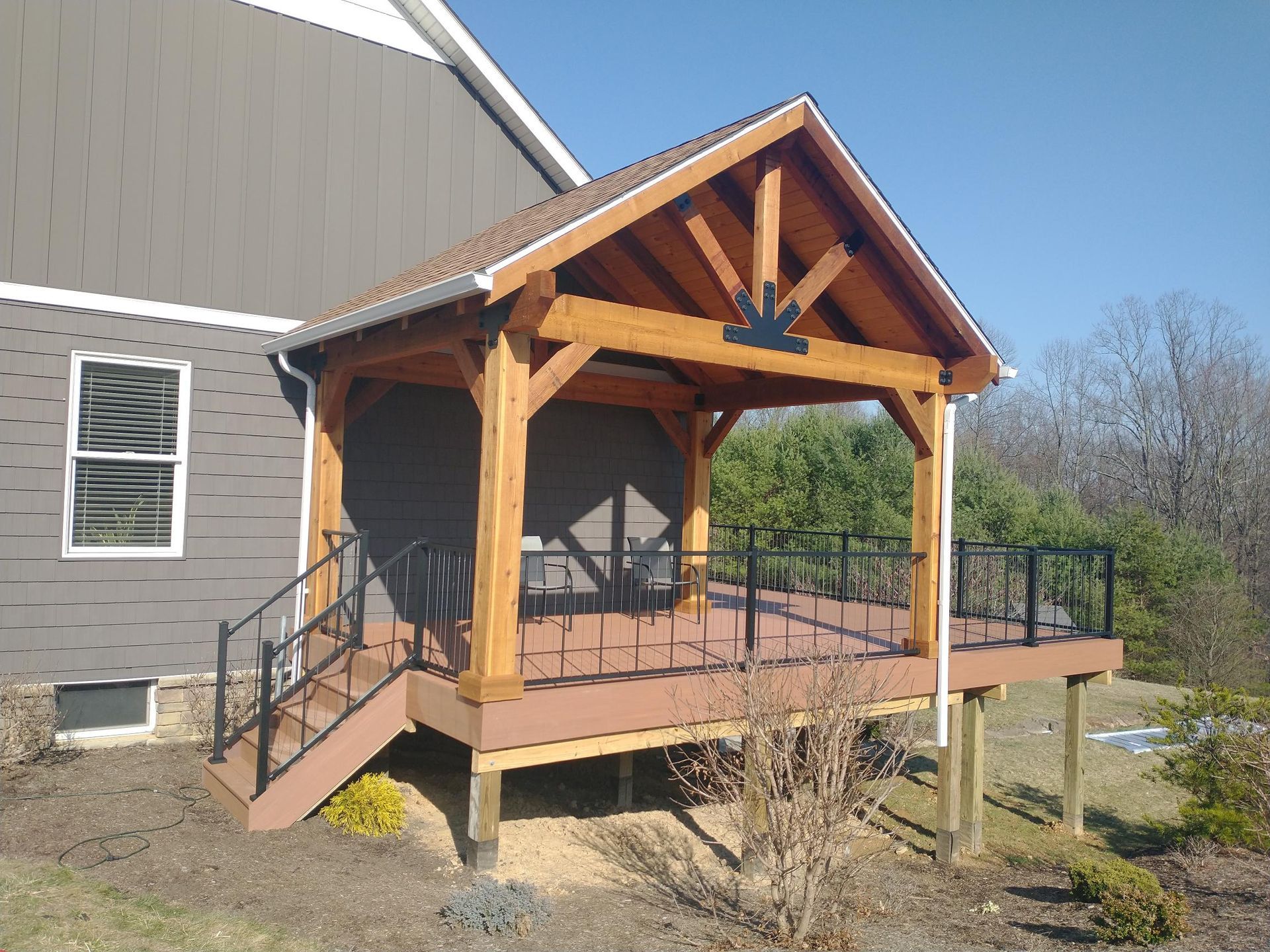 A light blue house with a white-trimmed elevated wooden deck, white railings, black metal balusters, and stairs.
