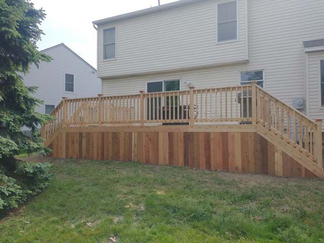 Close-up of wooden decking planks comparing a weathered gray board next to a freshly stained warm brown board.