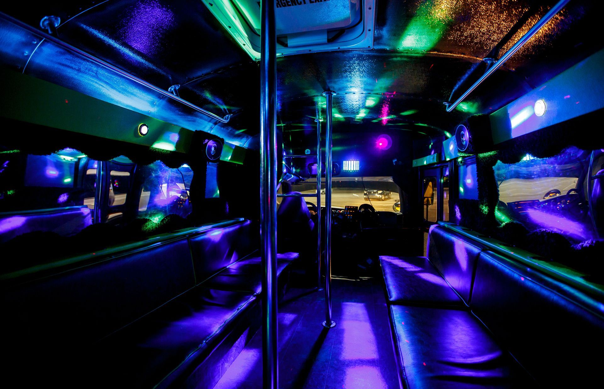 Empty neon-lit bus interior with blue, purple, and green lights and metal poles