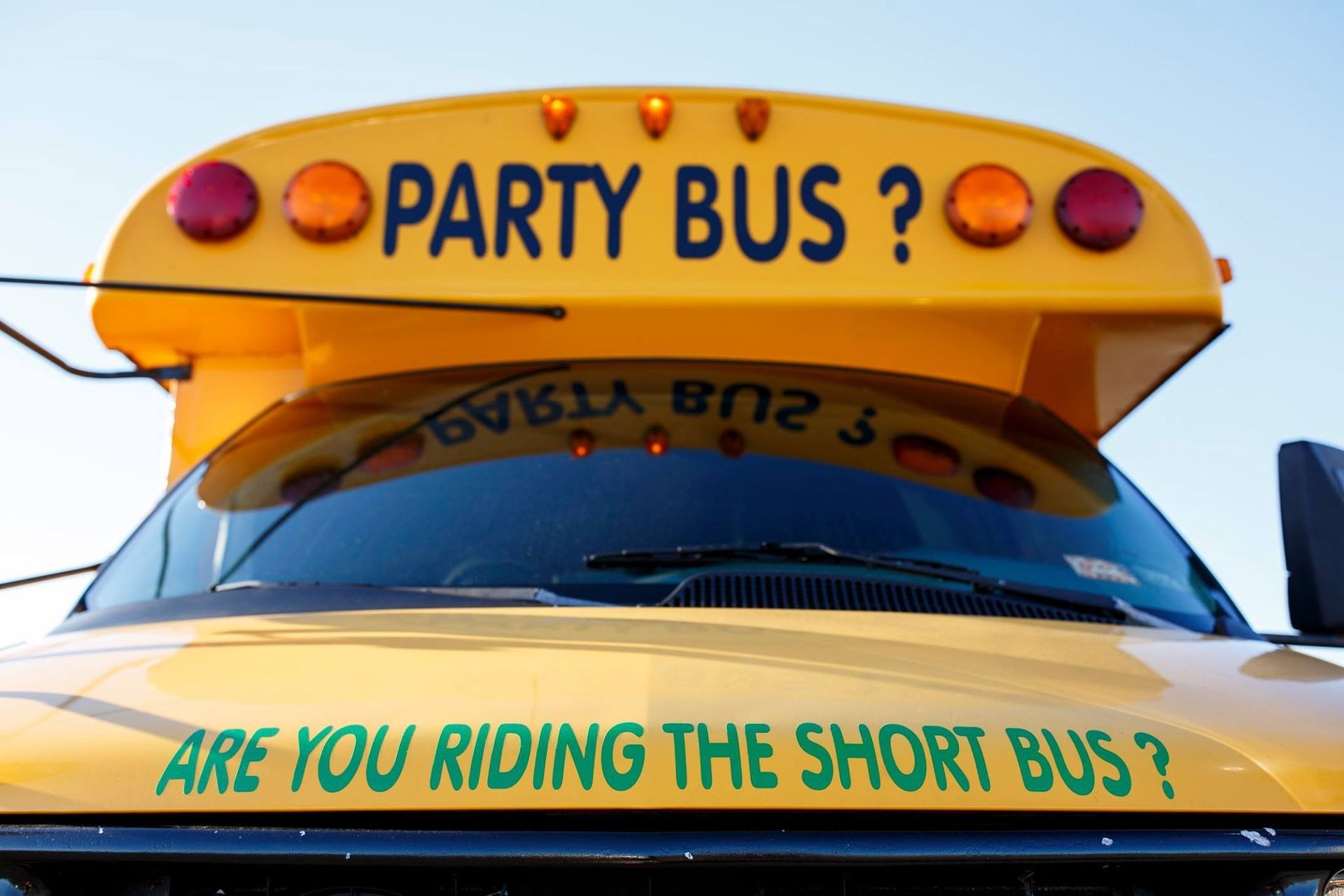 Yellow party bus with “ARE YOU RIDING THE SHORT BUS?” text on the front