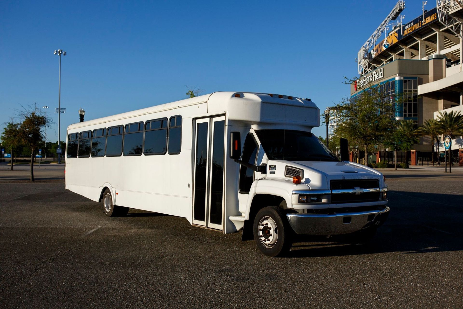 White shuttle bus parked outdoors in a lot under a clear blue sky