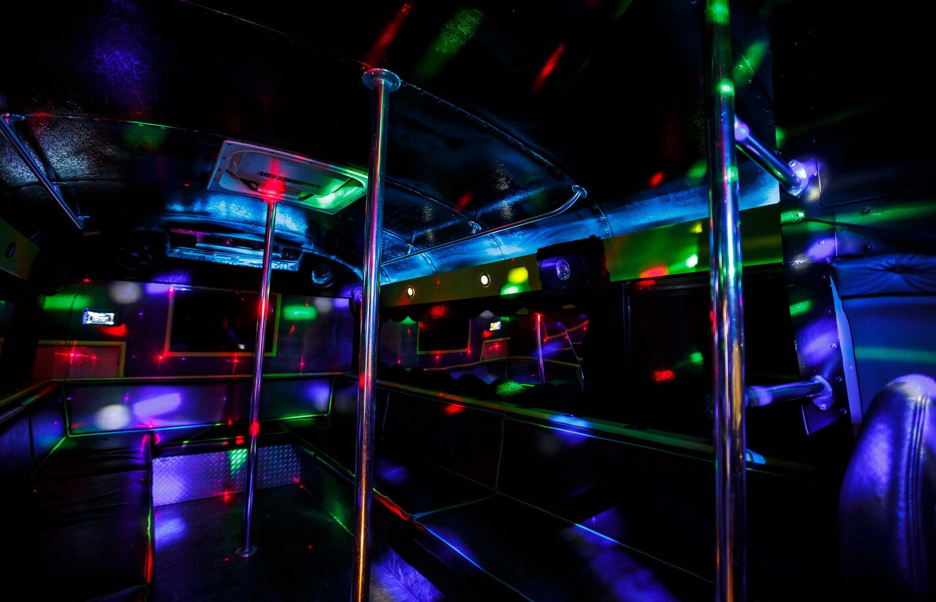 Colorful LED-lit interior of a bus or van, with chrome poles and reflective surfaces.