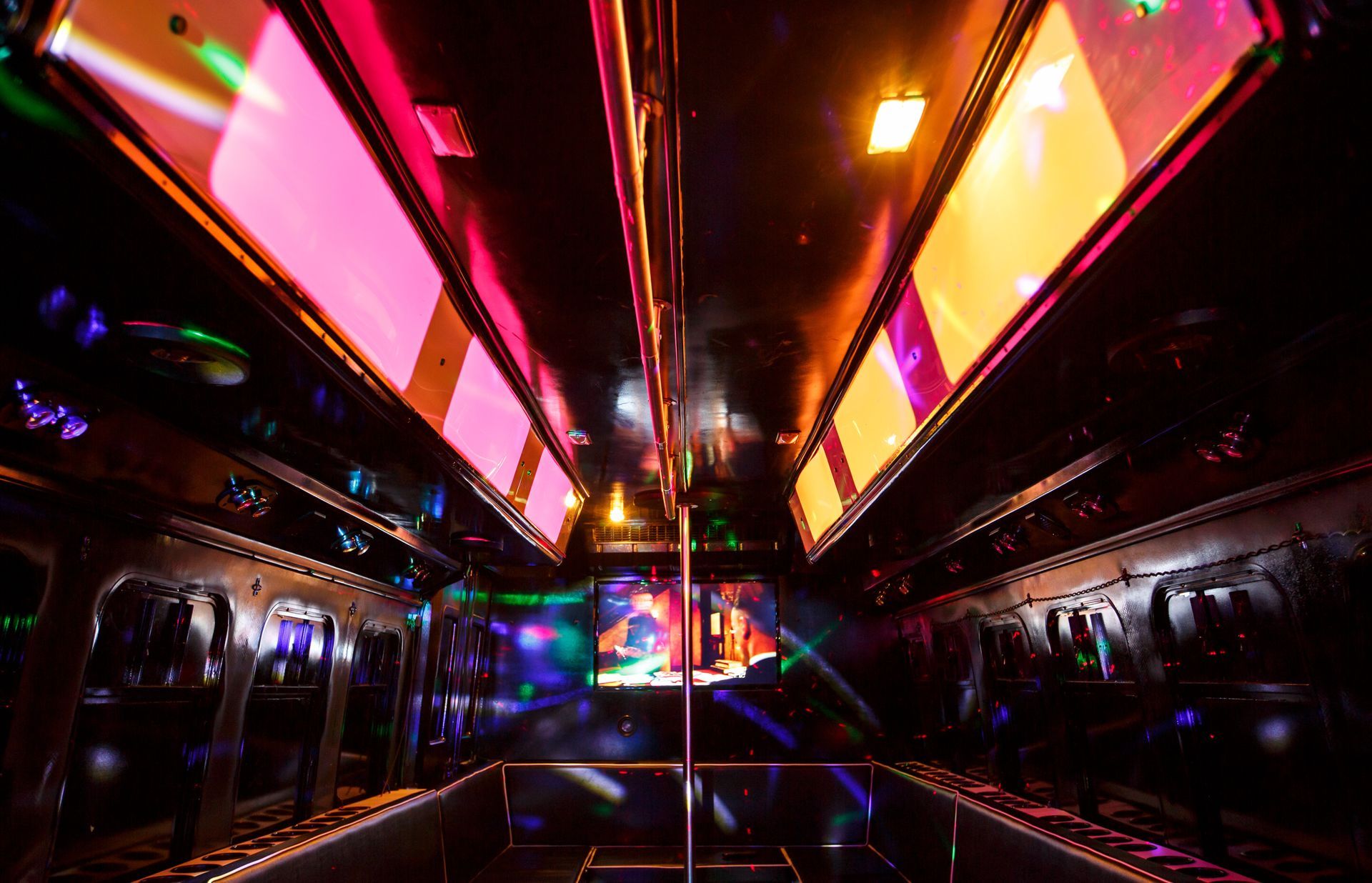 Neon-lit nightclub corridor with glowing pink, orange, and blue ceiling panels and mirrored walls