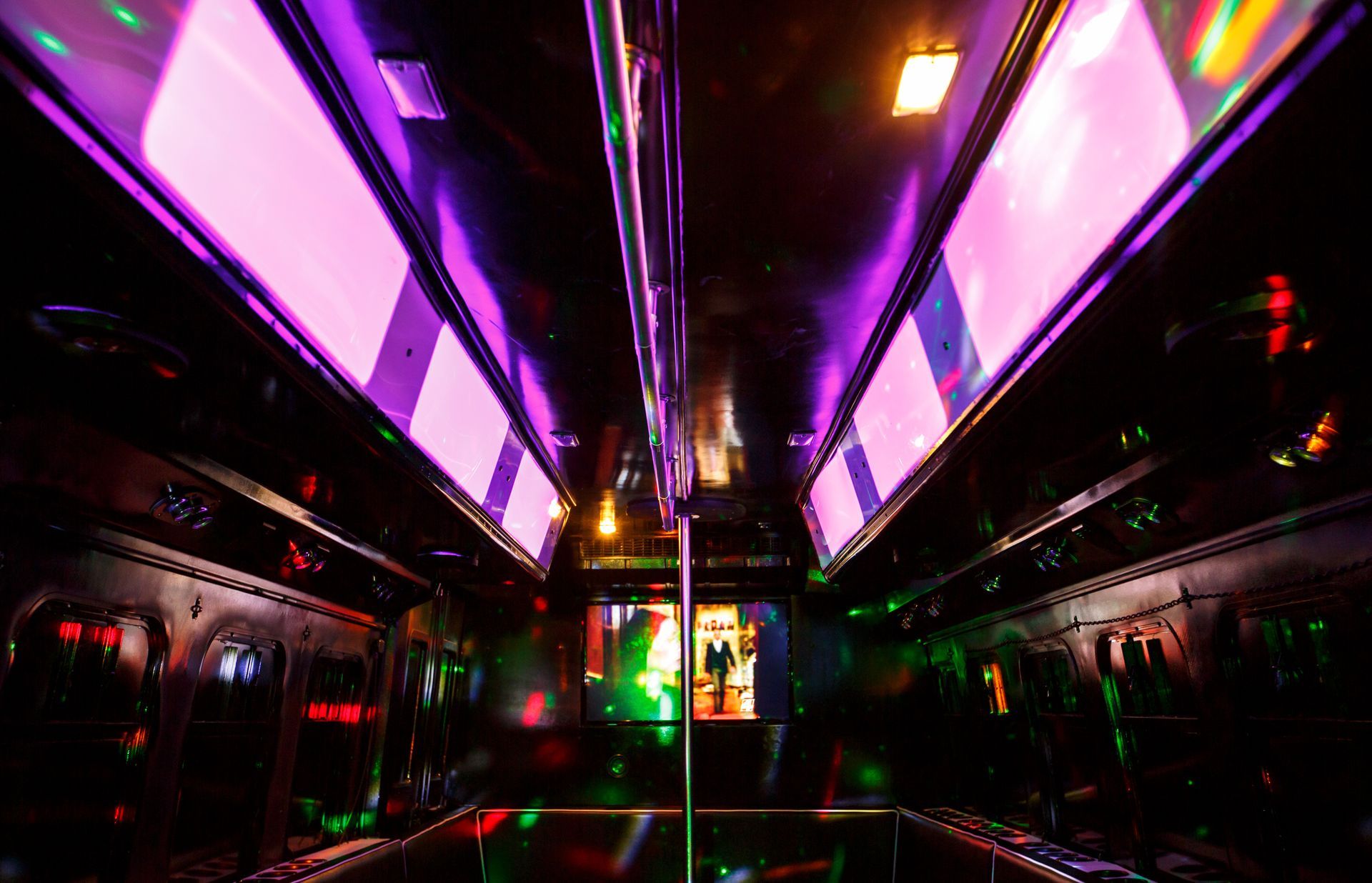 Neon-lit subway or bus interior with purple ceiling lights and a central pole at night