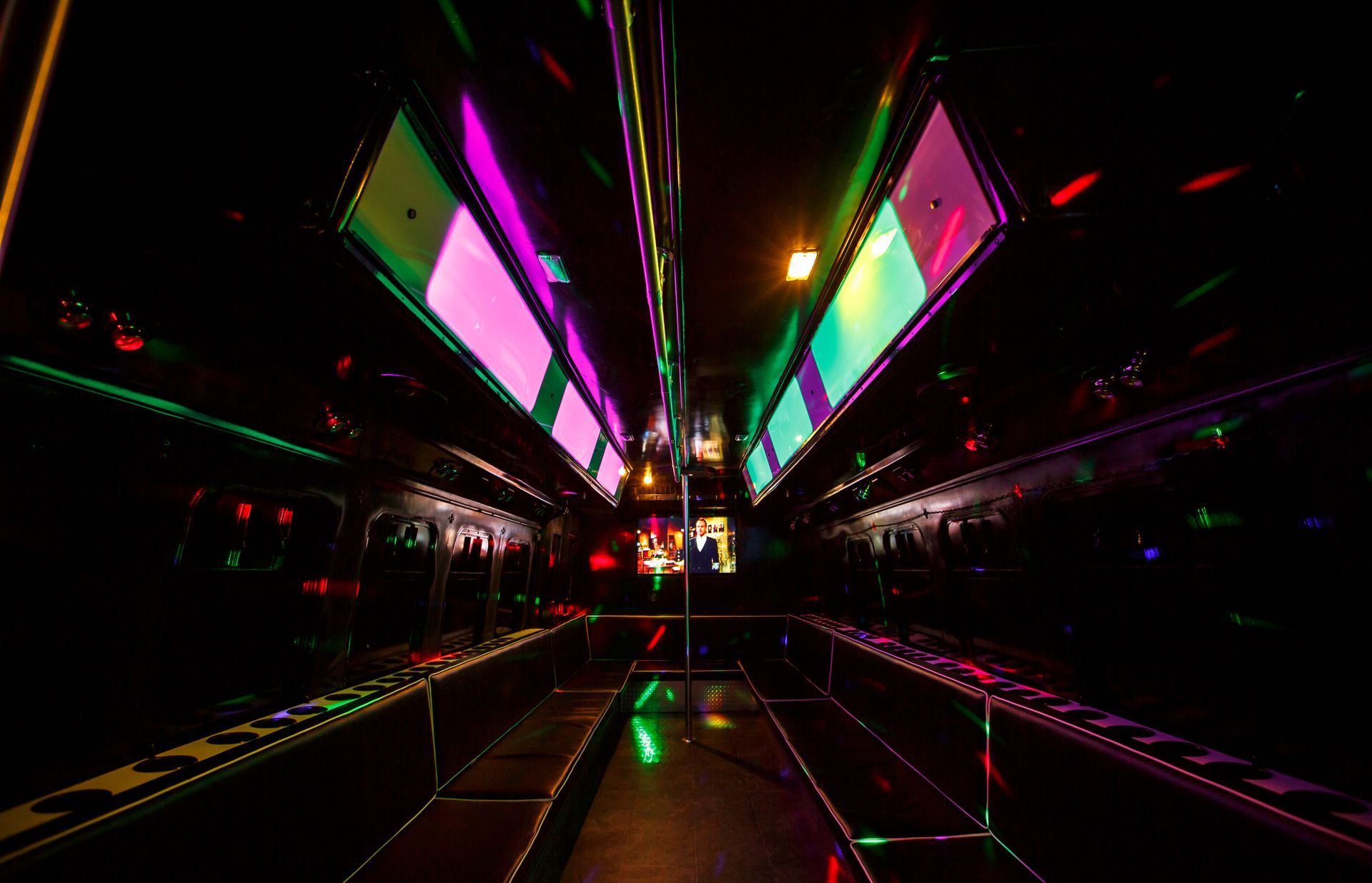 Neon-lit corridor with mirrored walls and bright pink, green, and yellow geometric lights reflecting on the floor