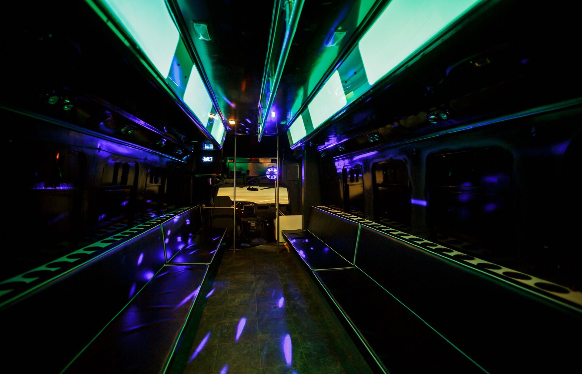 Neon-lit empty bus interior with green, blue, and purple lights reflecting on the floor
