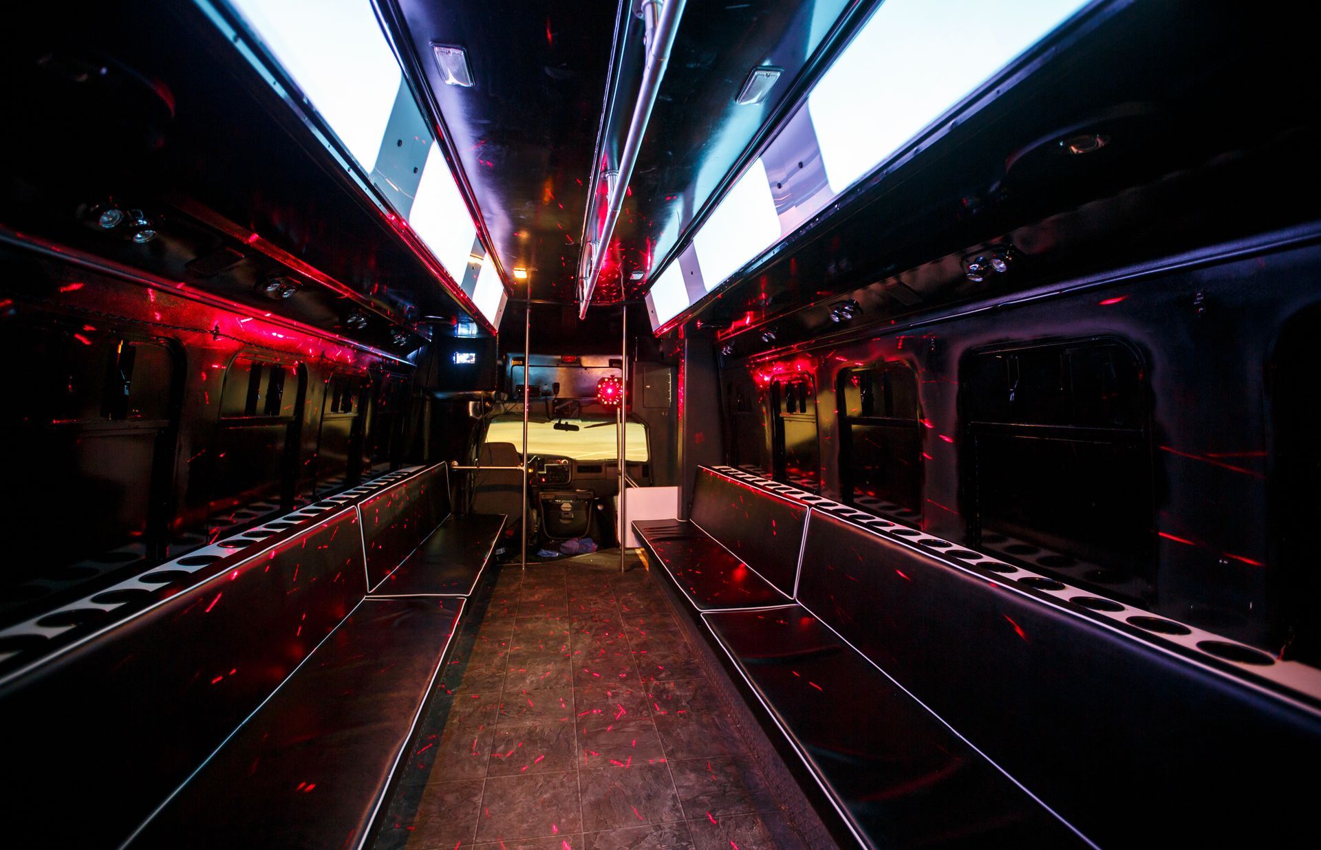 Empty bus interior with neon red and blue lights reflecting on dark seats and aisle