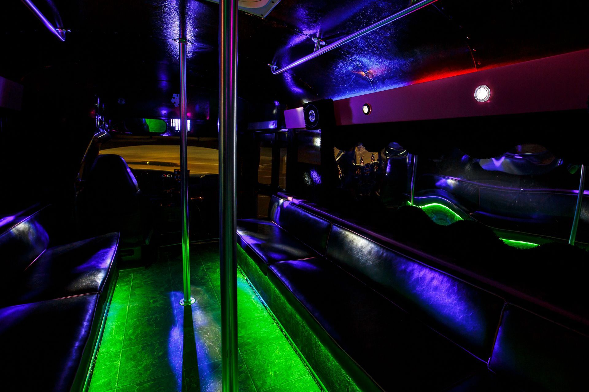 Dark neon-lit bus or club interior with green and purple lights and reflective surfaces