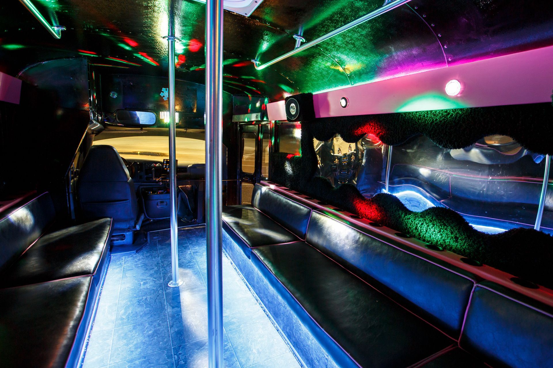 Colorful limousine interior with neon lights, leather seats, and a central pole