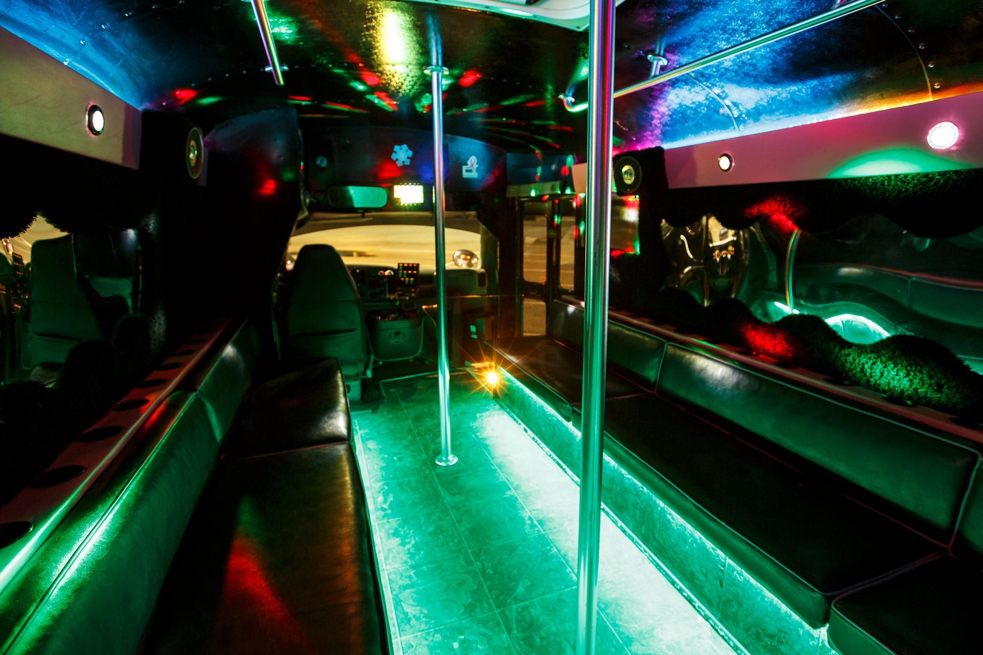 Empty nightclub interior with neon green and red lighting, mirrored walls, and a dance pole