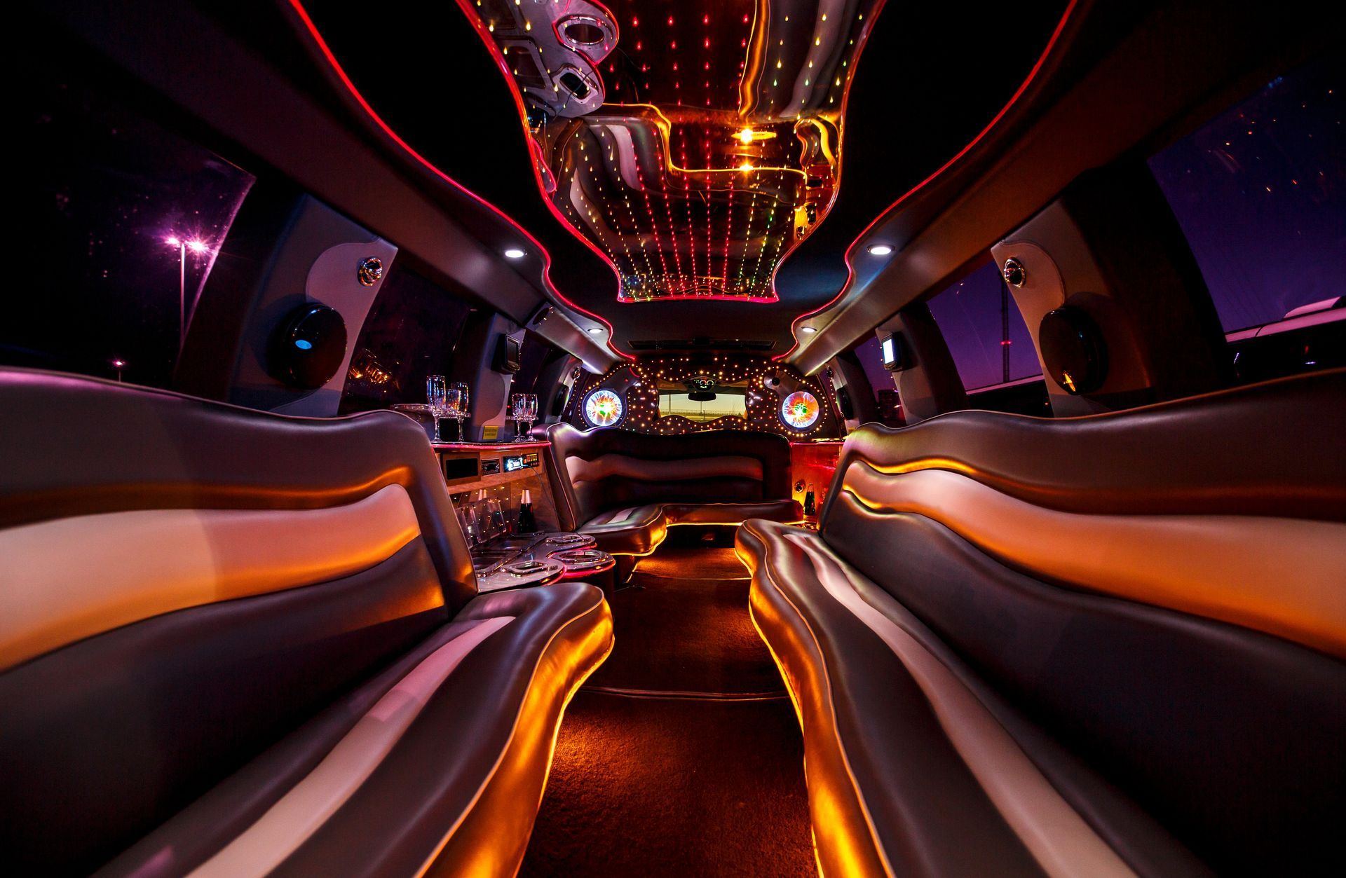 Futuristic lounge interior with glowing orange and purple lights, curved seats, and a mirrored ceiling