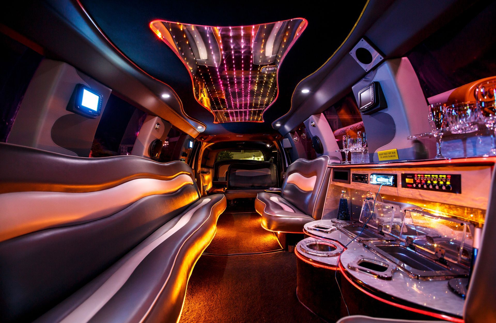 Luxurious nightclub limousine interior with neon lighting, leather seating, and a bar area