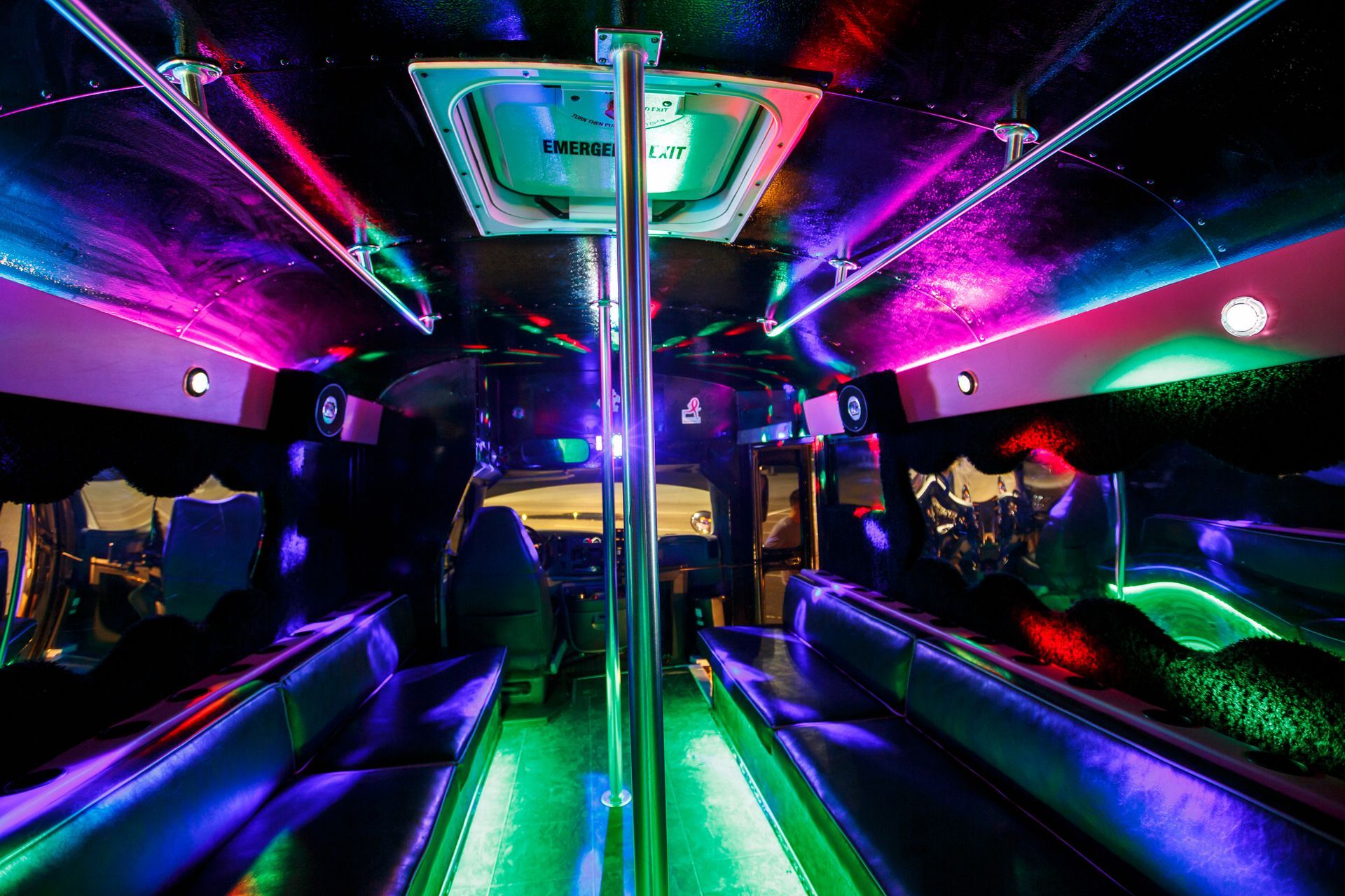 Neon-lit party bus interior with colorful LED lights and chrome poles