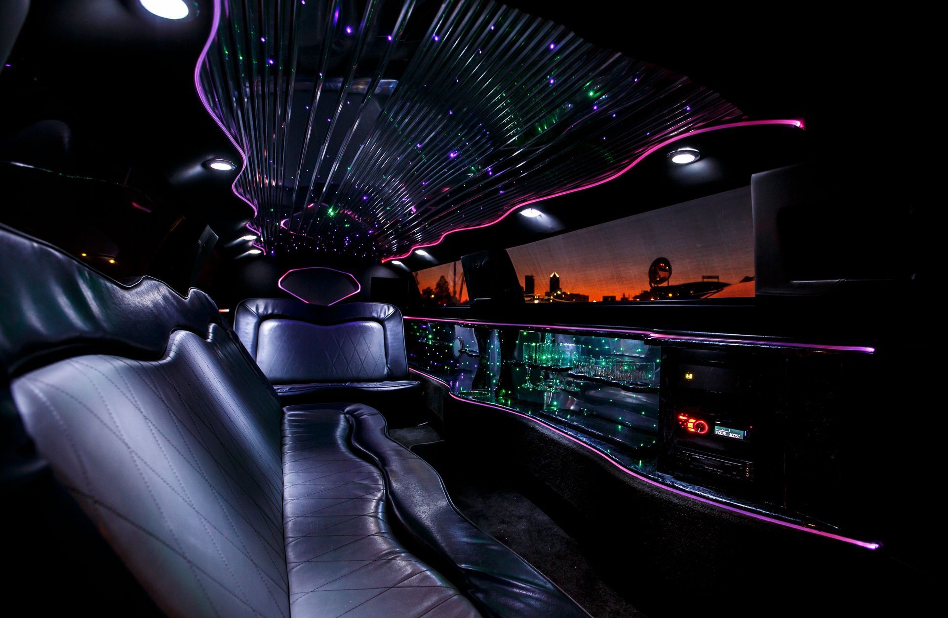 Futuristic luxury limousine interior with purple LED lighting and glossy black seating at dusk