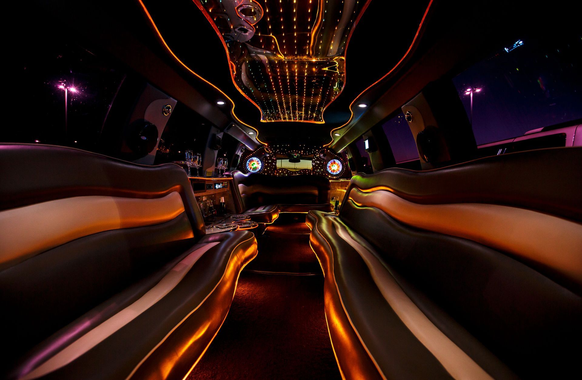 Luxurious limousine interior with orange ambient lighting and city lights visible through the windows