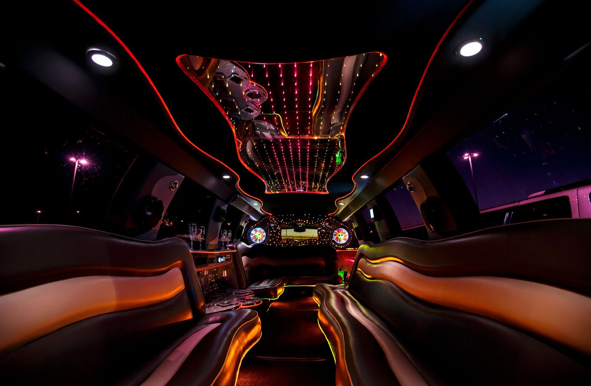 Neon-lit luxury car interior at night with glowing red and orange accents and city lights outside