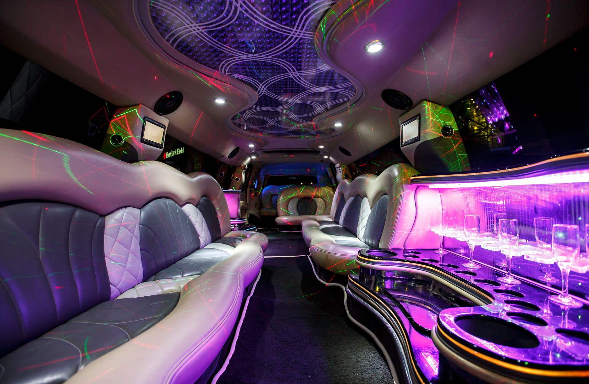 Lavishly lit limo interior with white seats, purple neon accents, and a glossy bar console
