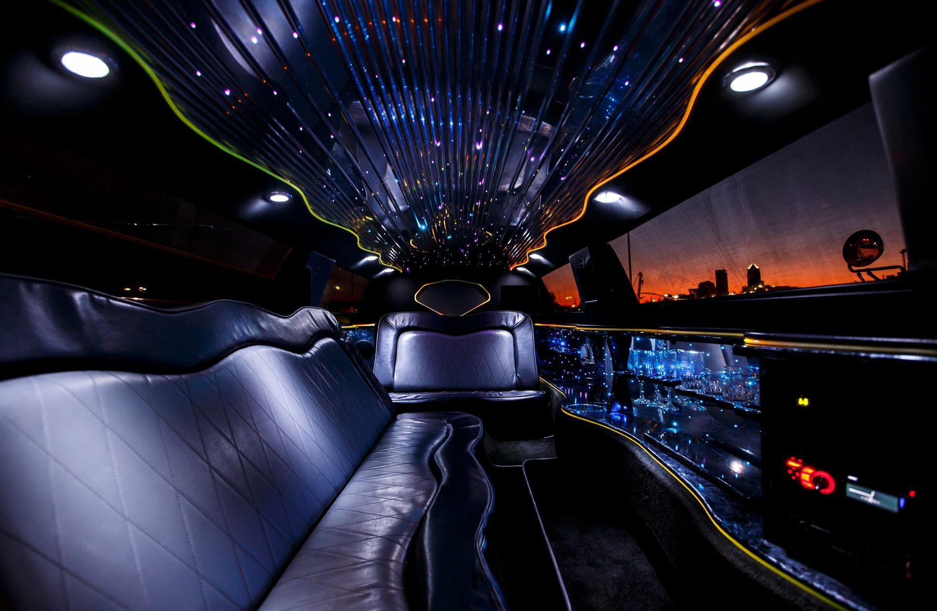 Luxury limousine interior with starry ceiling lights and city sunset view through the windows