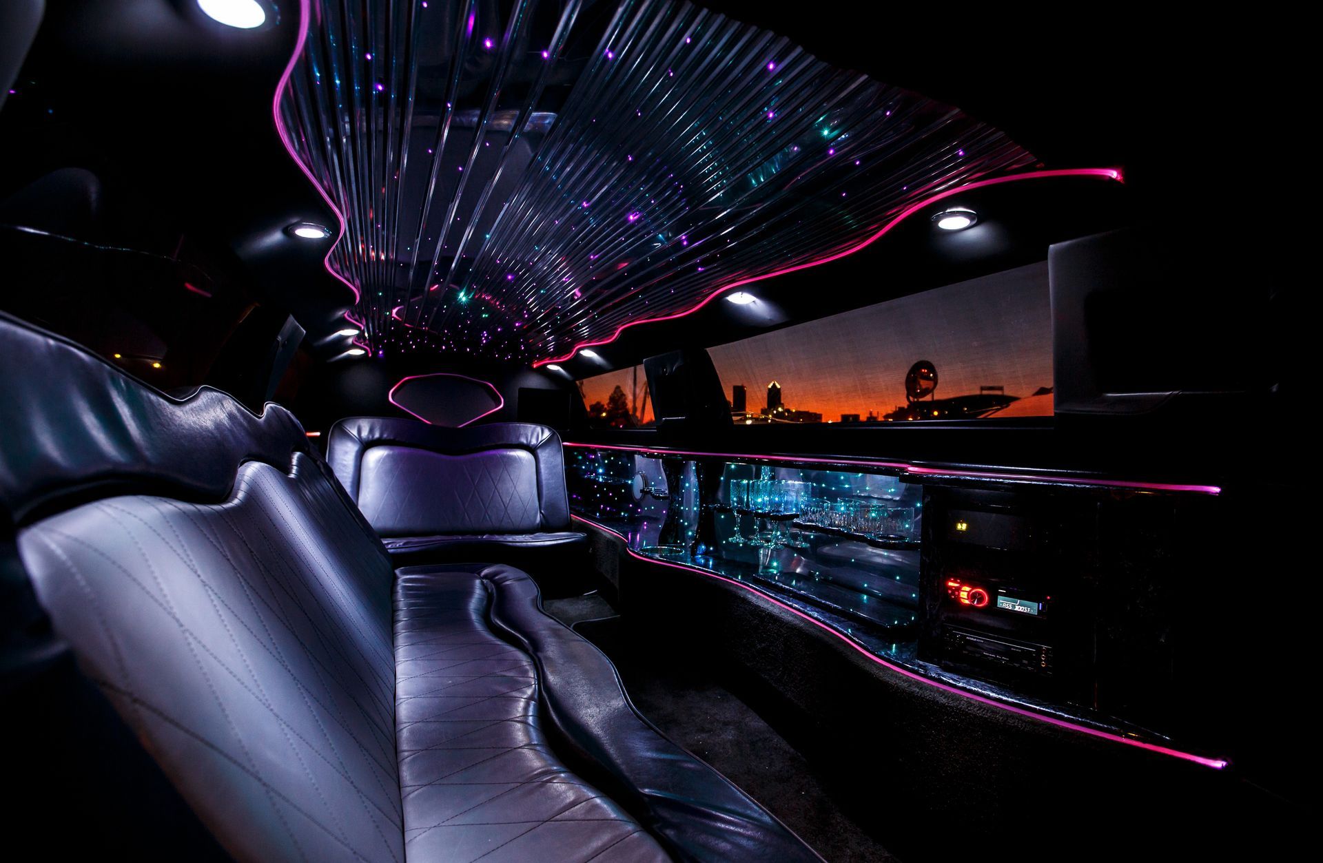 Luxurious nightclub interior with silver seats, neon ceiling lights, and a city view at sunset
