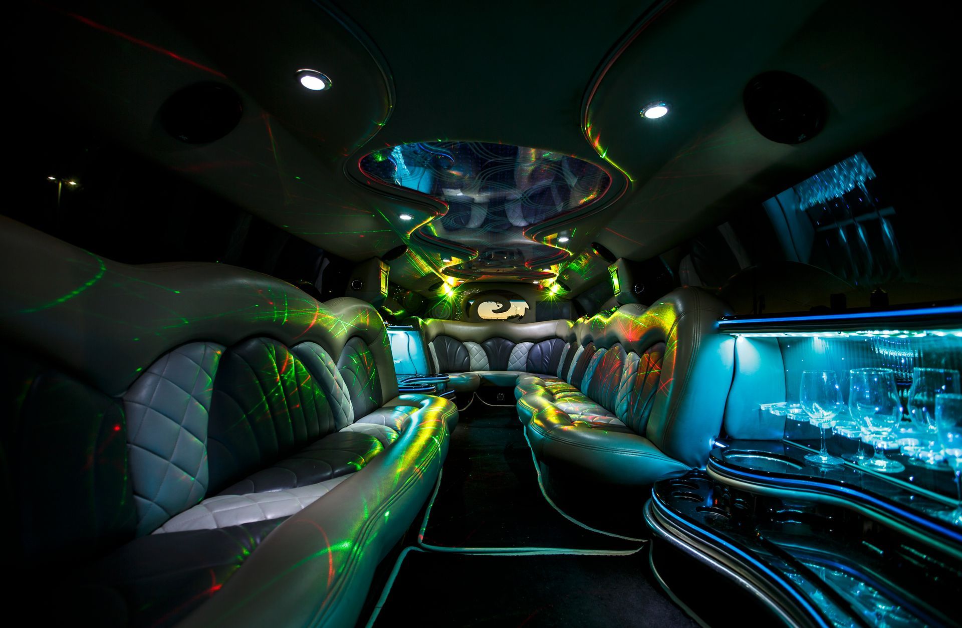 Interior of a luxury limousine with neon lighting, leather seats, and a glowing blue aquarium-style side panel