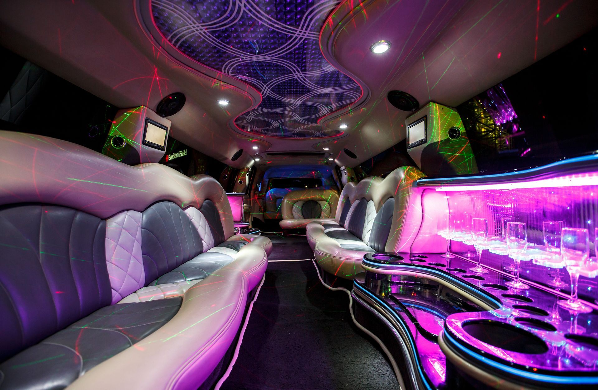 Lavishly lit limousine interior with purple neon lights, leather seats, and a starry ceiling