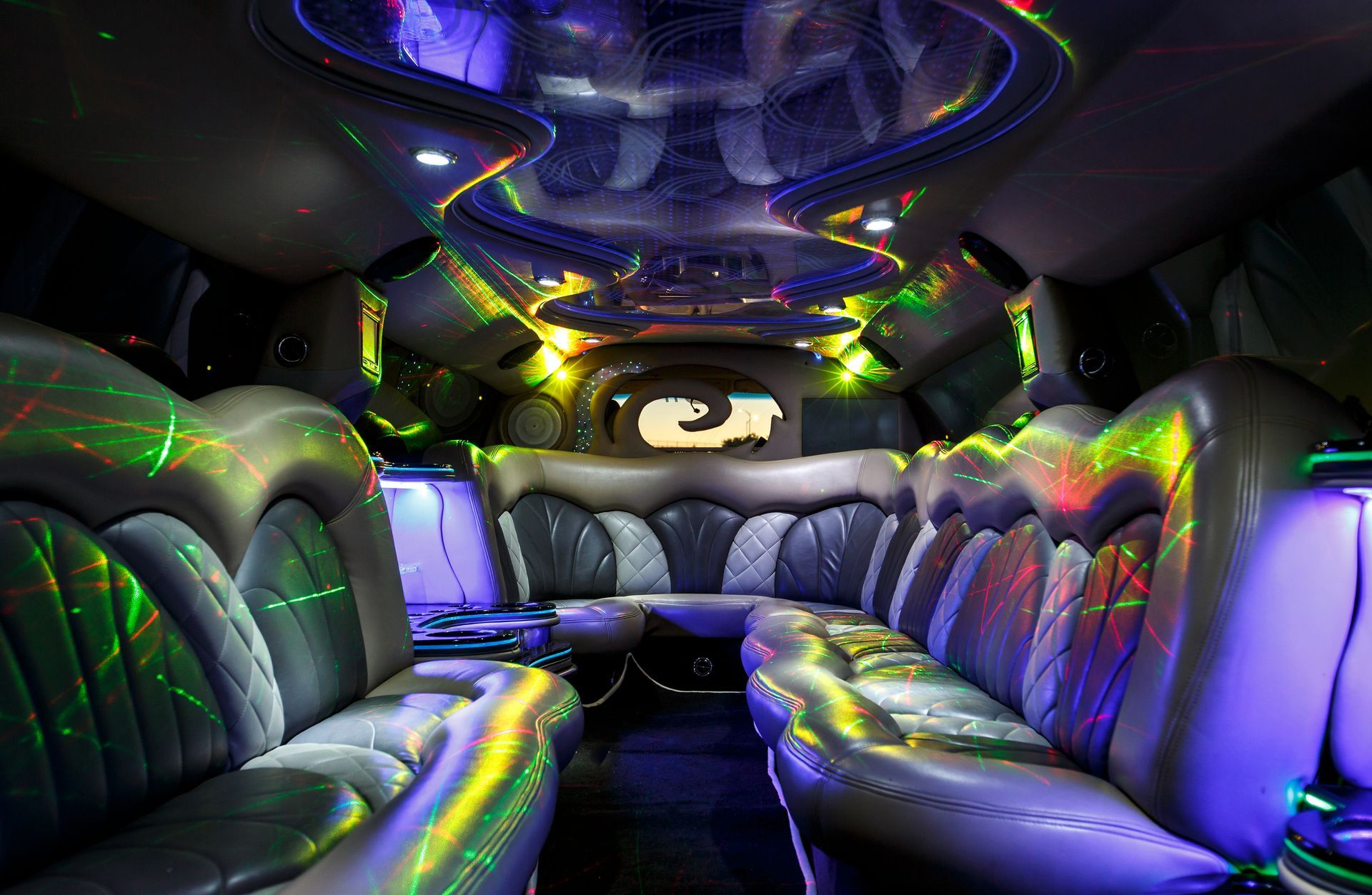 Colorful illuminated limousine interior with black leather seats and neon lighting