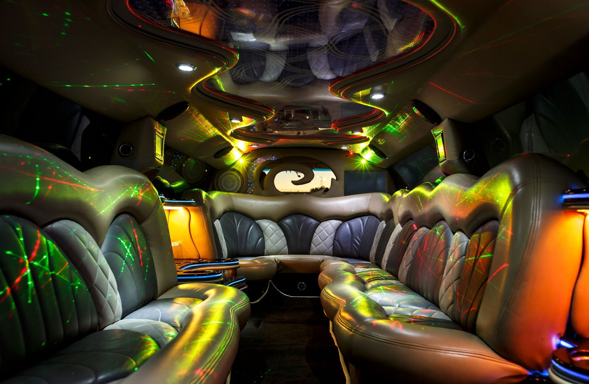 Interior of a flashy limousine with leather bench seats and colorful neon lighting