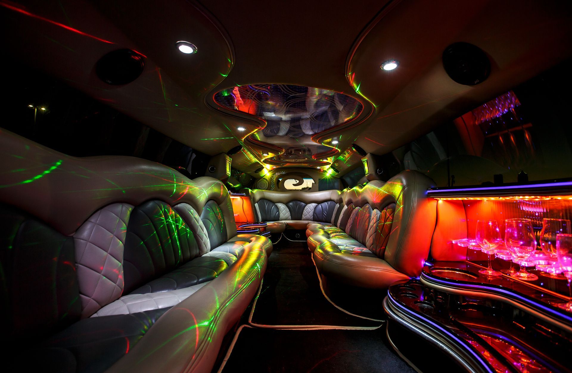 Luxurious limousine interior with leather seats, neon lighting, and a glossy bar area