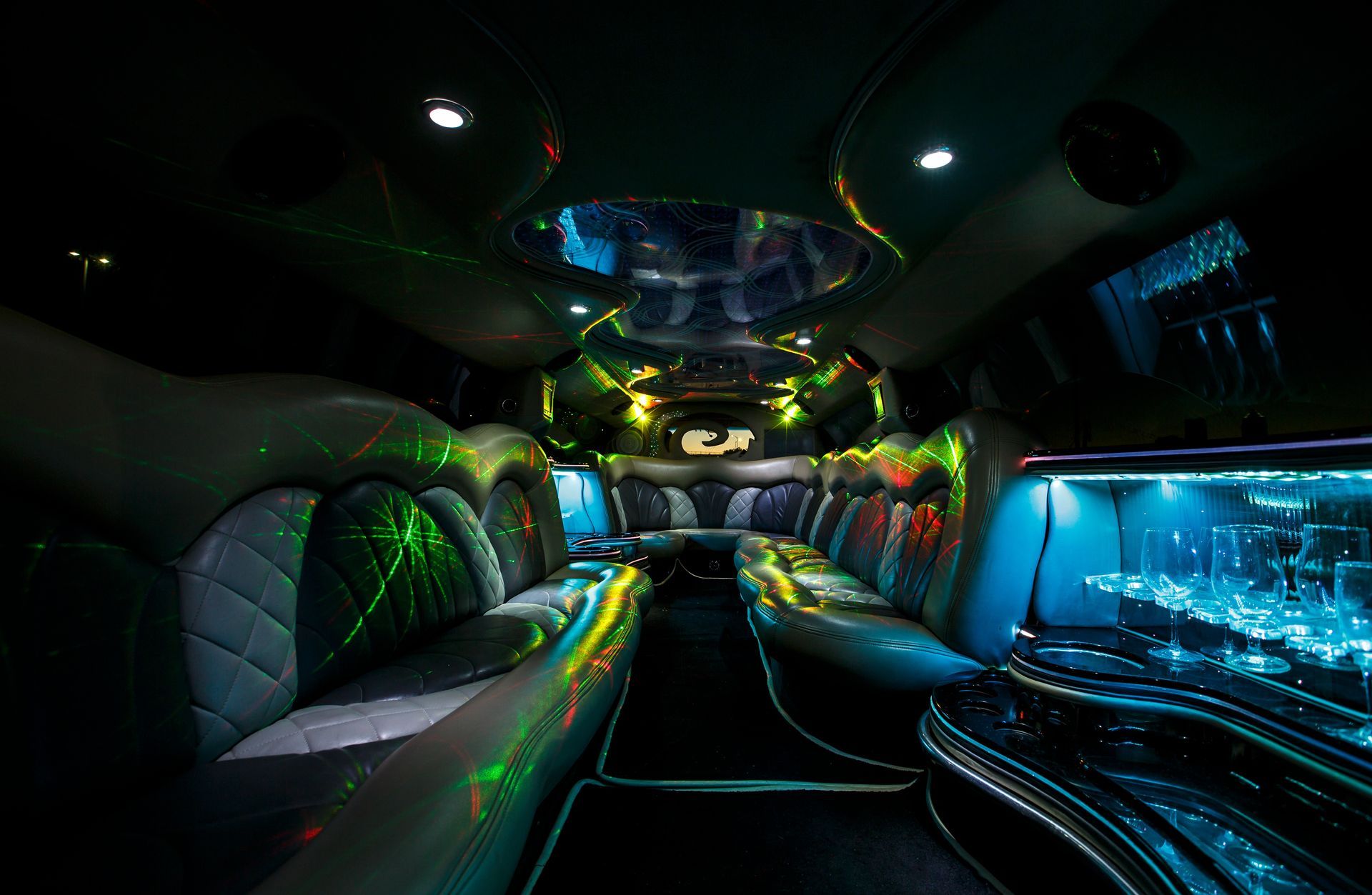 Interior of a luxury limousine with neon lighting, leather seats, and blue-lit windows.