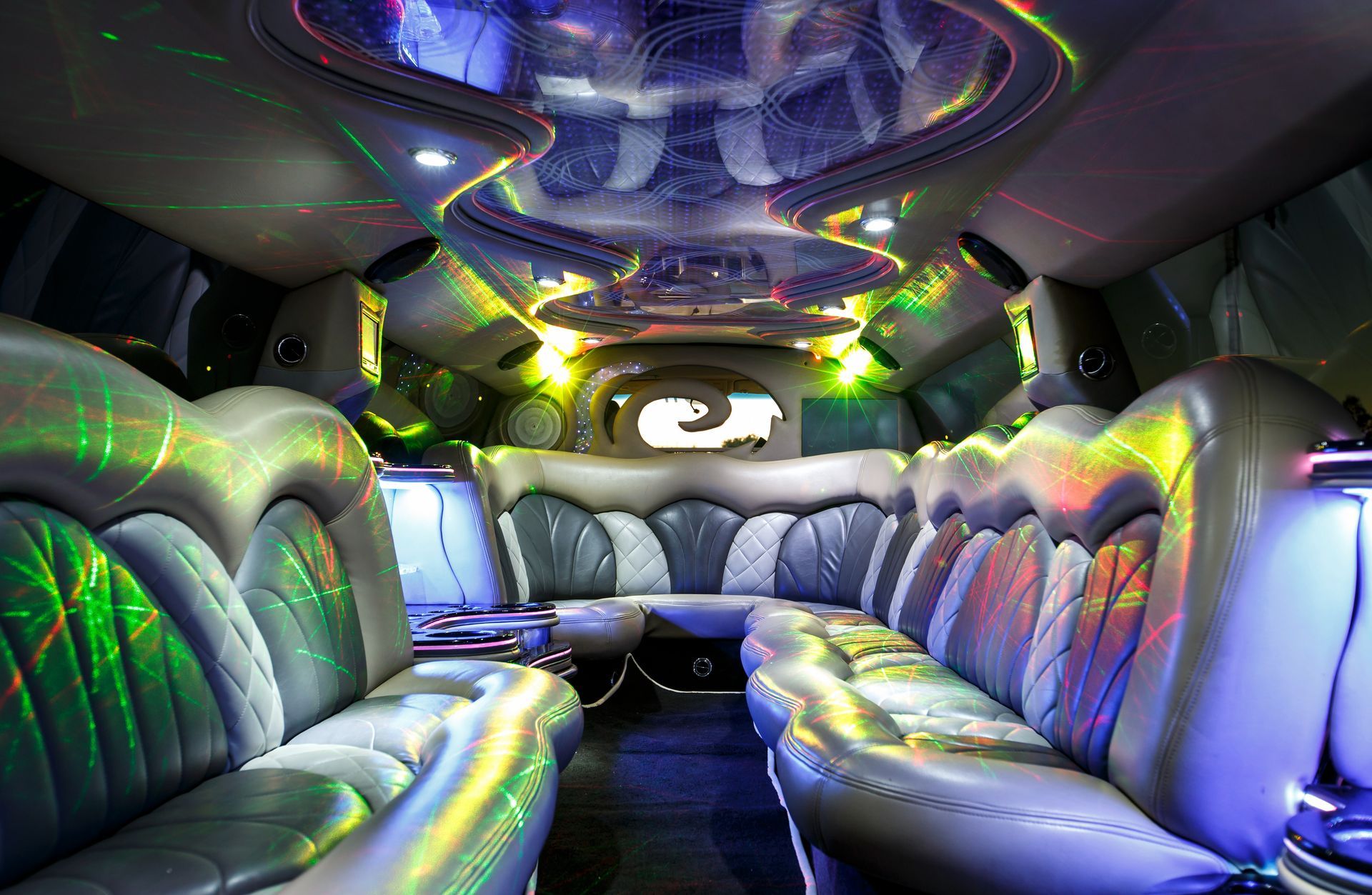 Bright limousine interior with white leather seats and colorful neon ceiling lights
