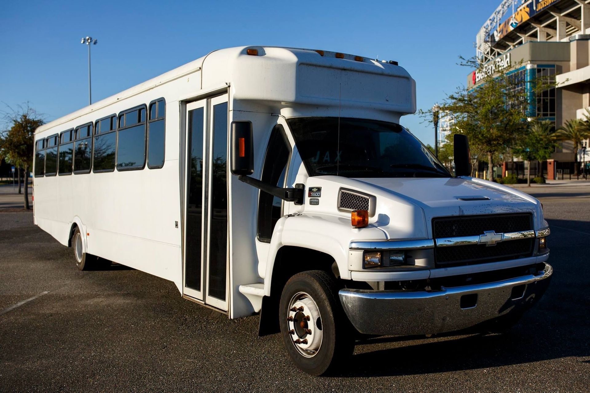 White shuttle bus parked outdoors on a sunny street, front door open