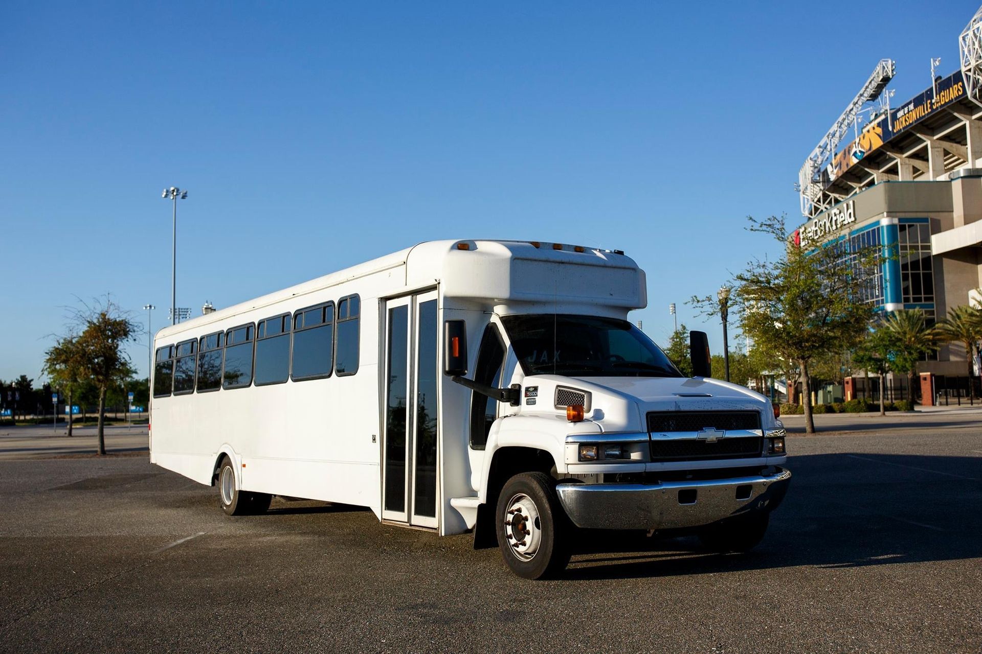 White shuttle bus parked outdoors with its door open on a sunny day