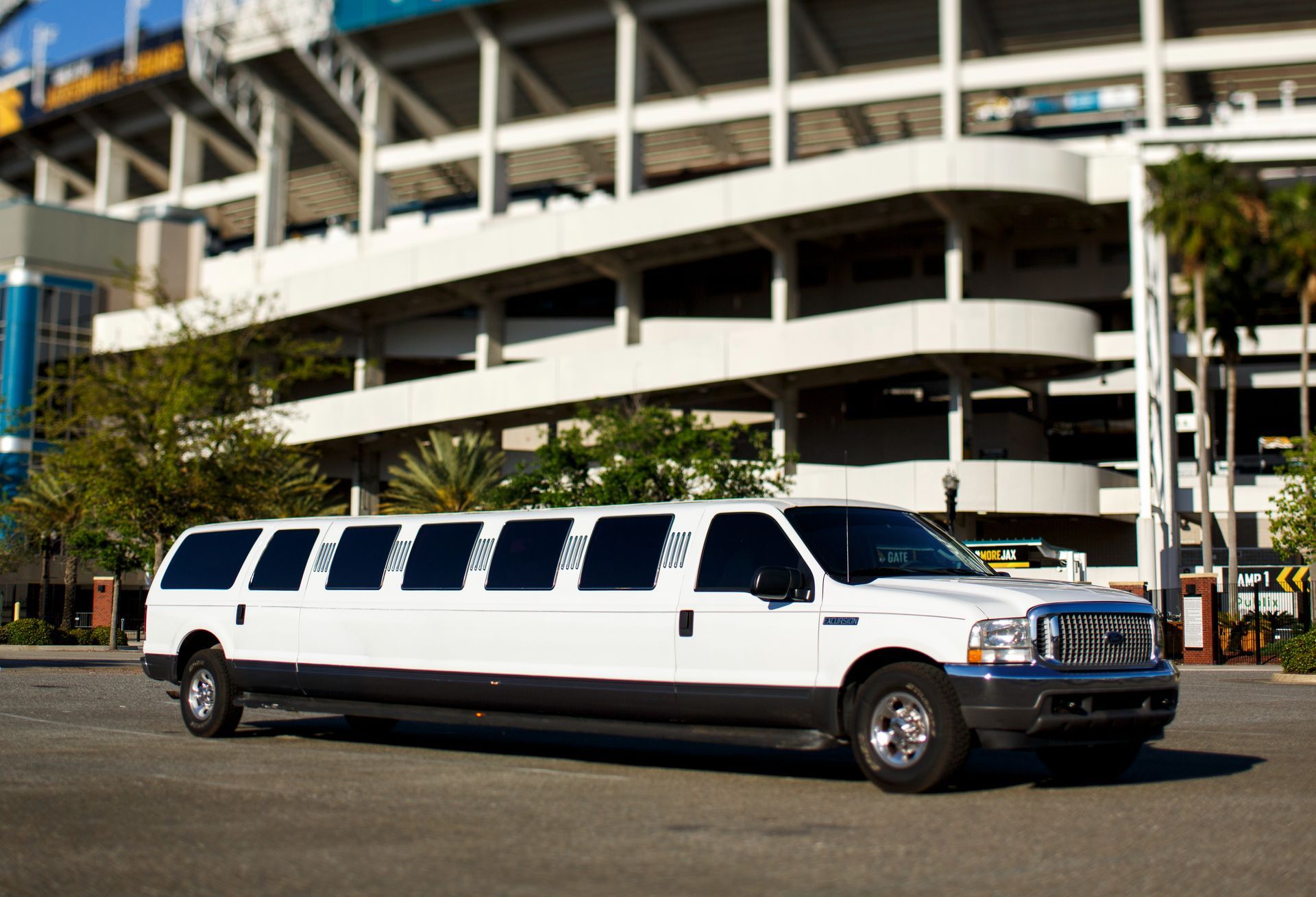 White stretch limousine parked in front of a multi-level building in daylight