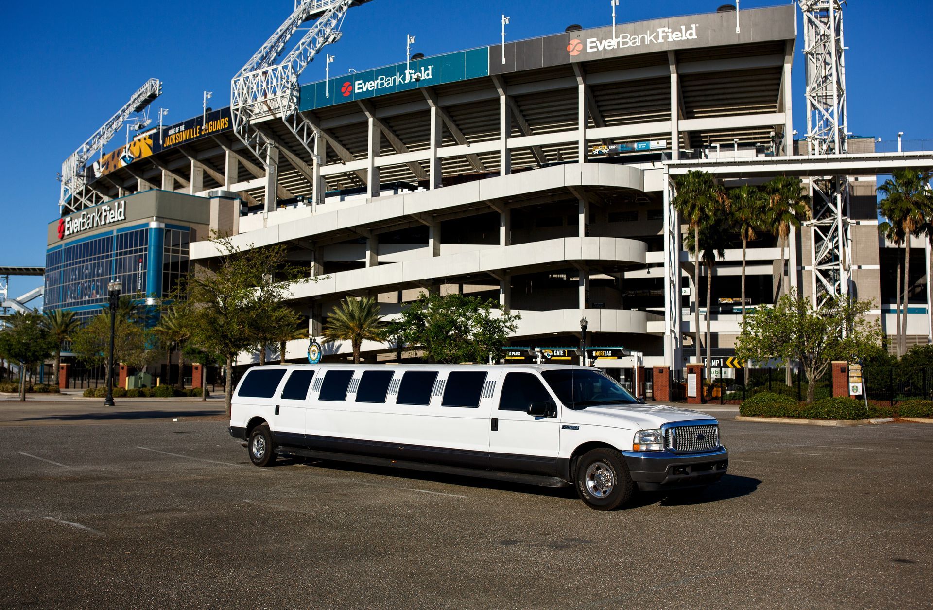 White stretch limousine parked outside a stadium under construction on a sunny day