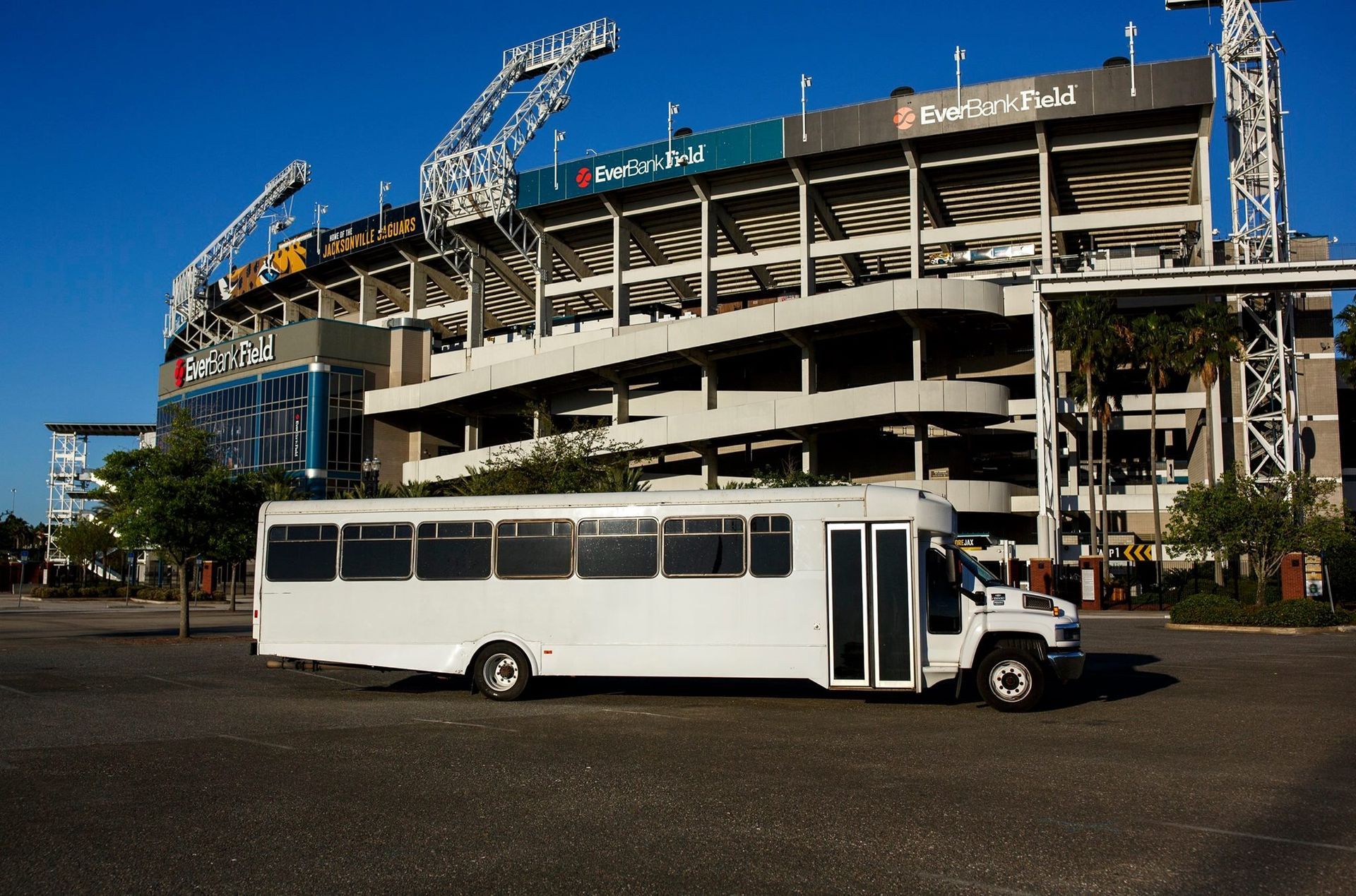 White shuttle bus parked in front of a stadium under construction