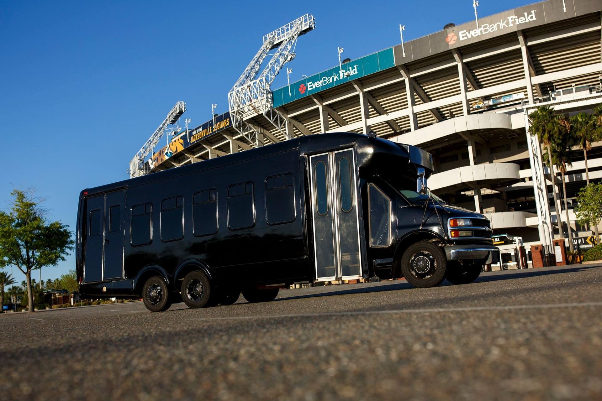 Black truck parked outside a stadium under a clear blue sky.