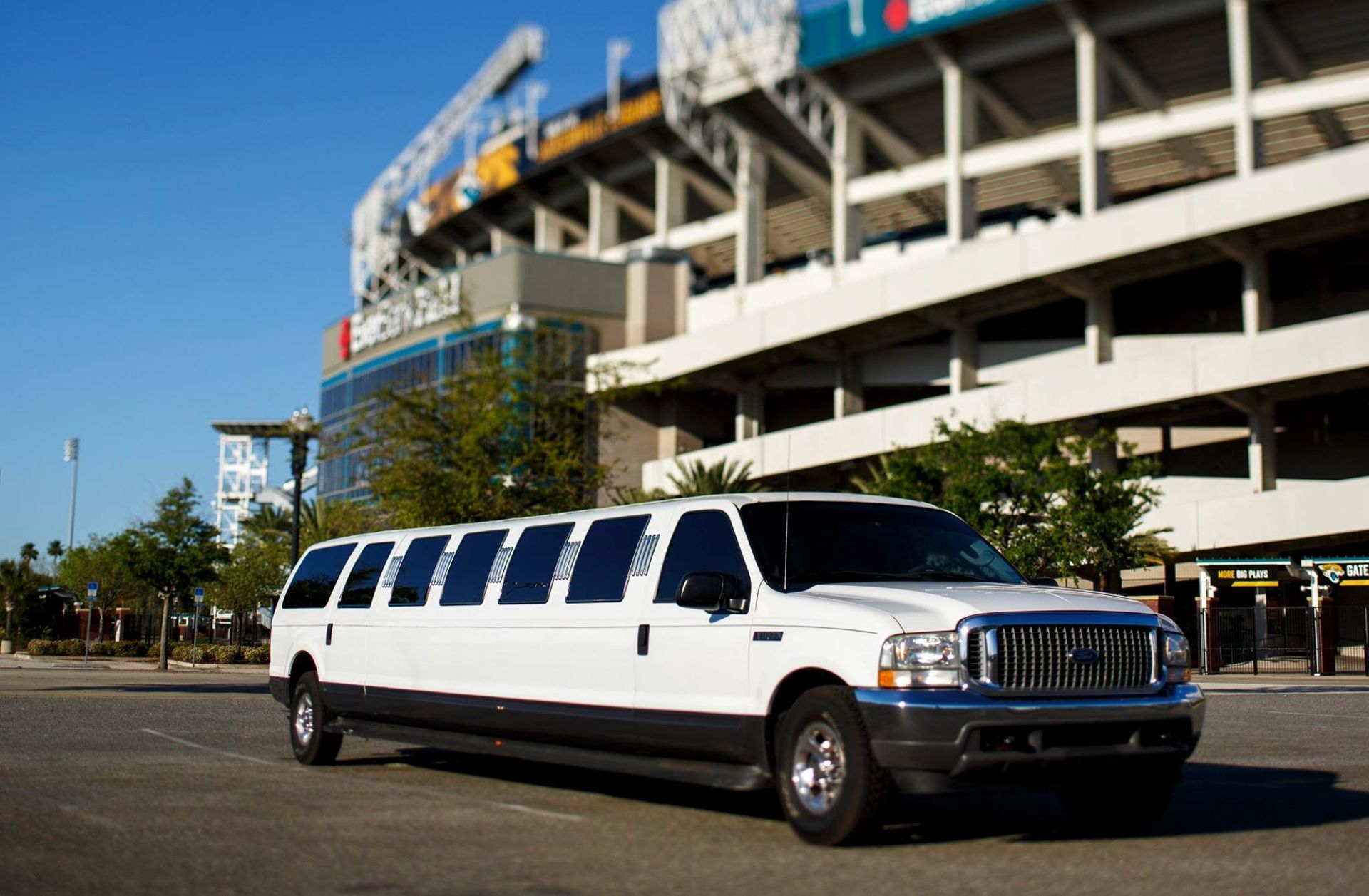 White stretch limousine parked outside a stadium on a sunny day
