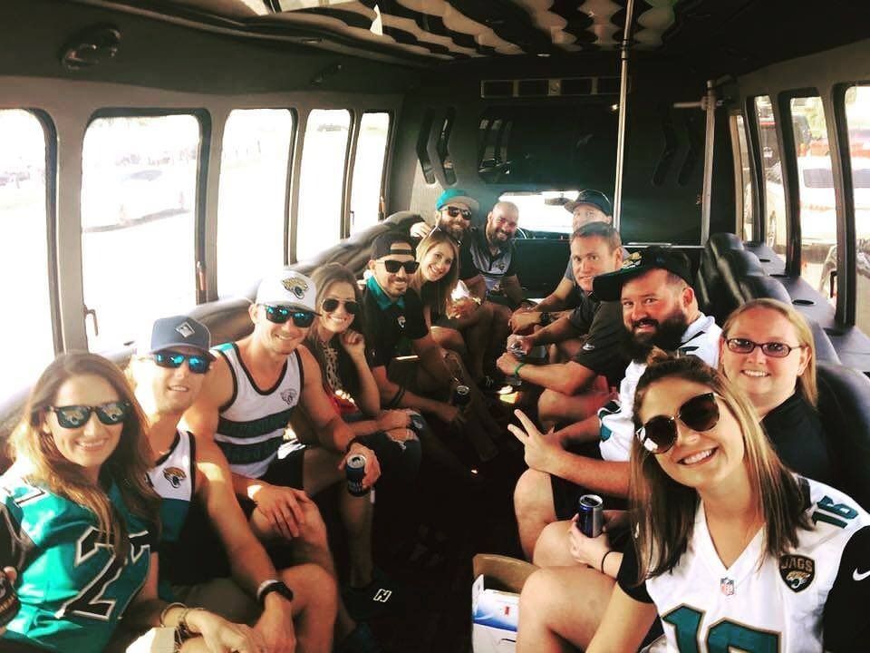 Group of people seated together inside a bus, smiling and posing for a group selfie.