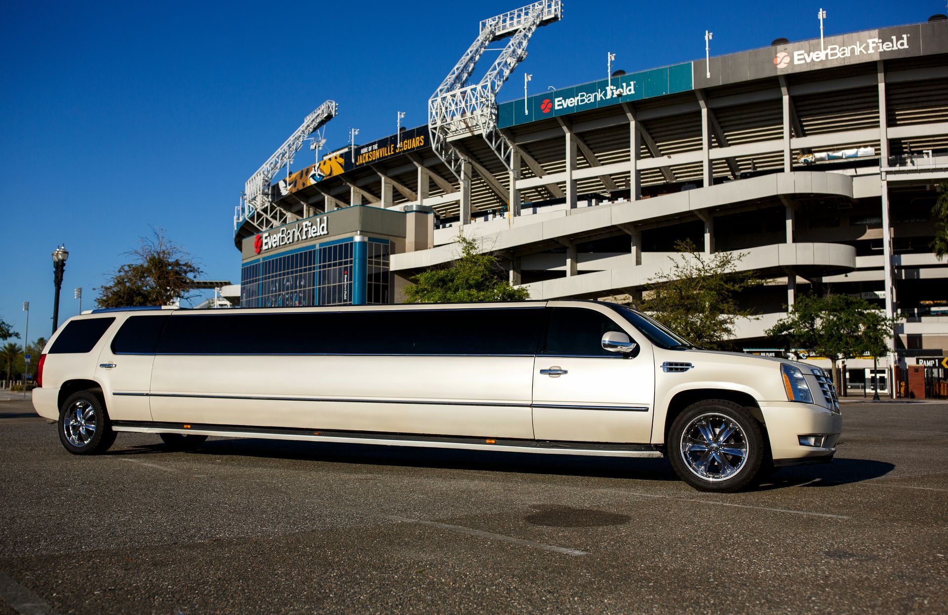 White stretch limousine parked outside a stadium under a clear blue sky