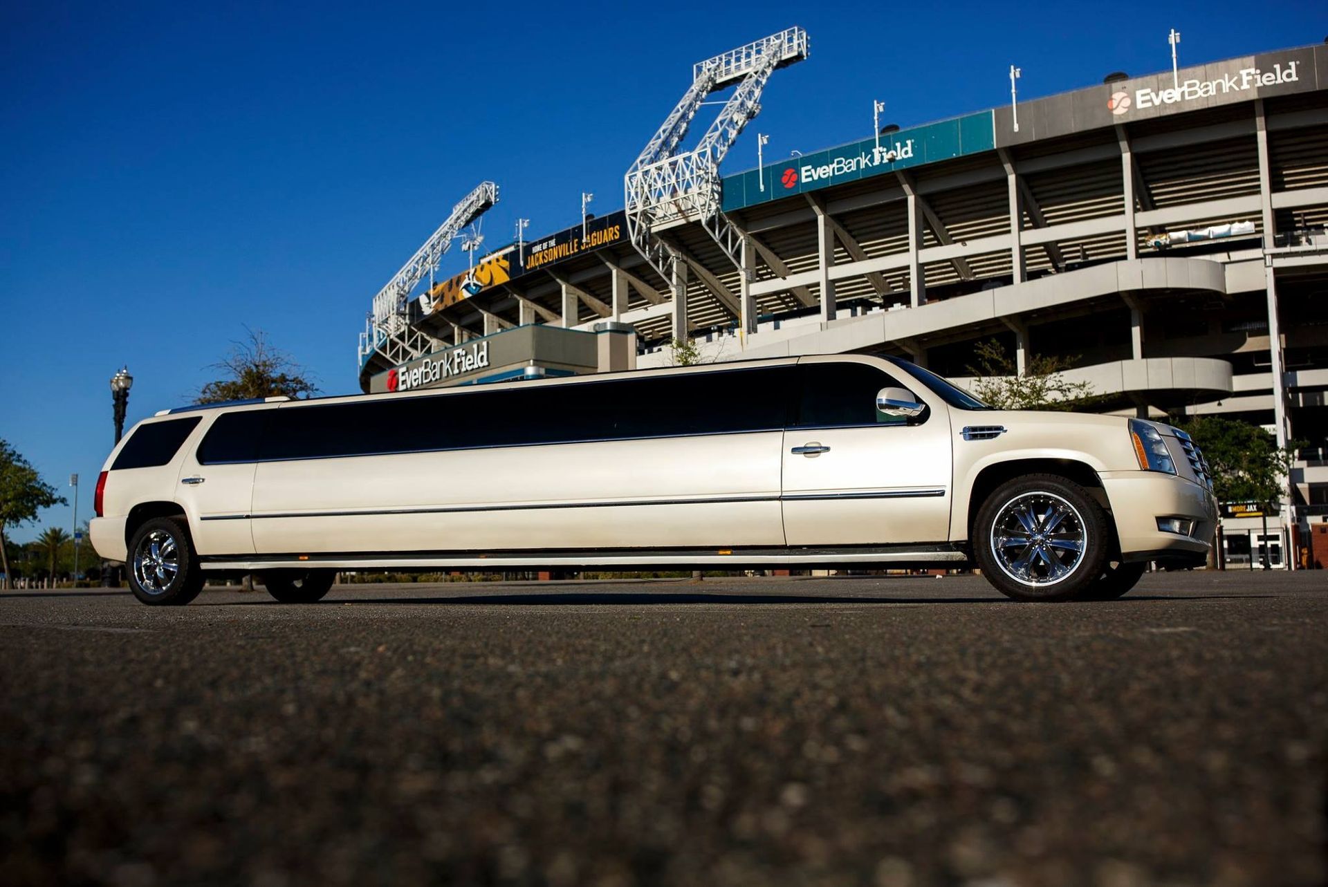 White stretch limousine parked outside a stadium on a sunny day