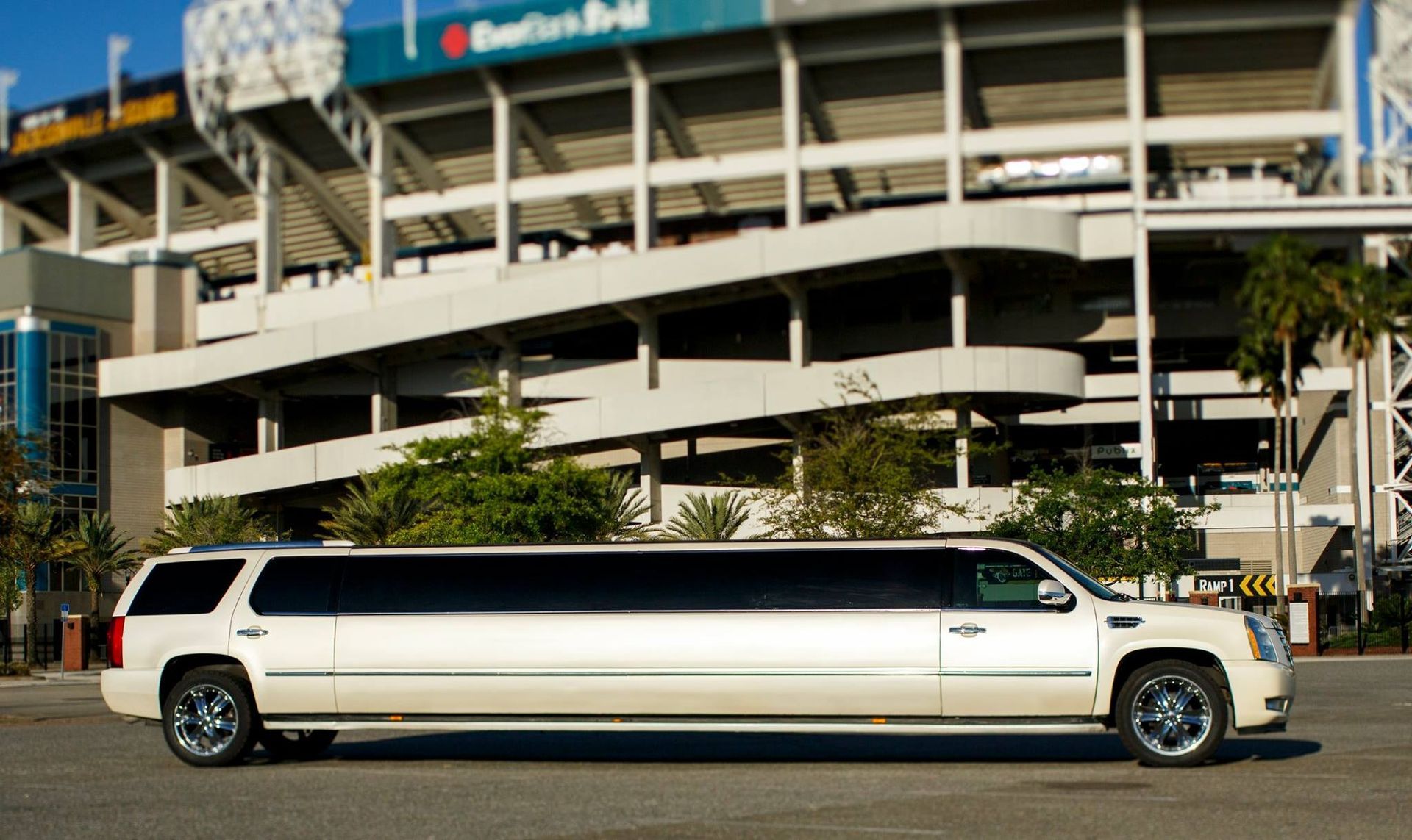 White stretch limousine parked outside a stadium in daylight