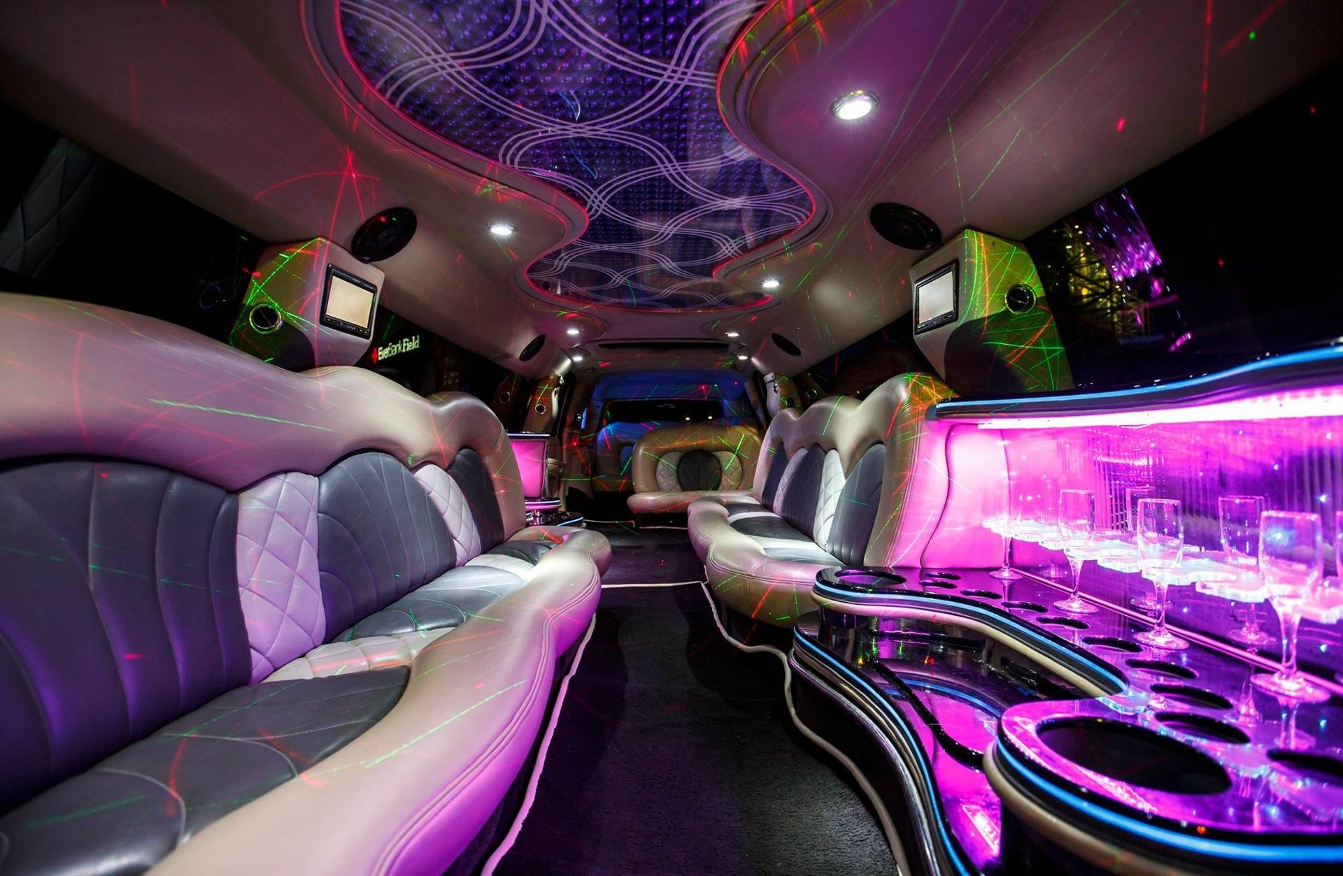 Luxurious limo interior with purple neon lighting, leather seats, and mirrored ceiling accents