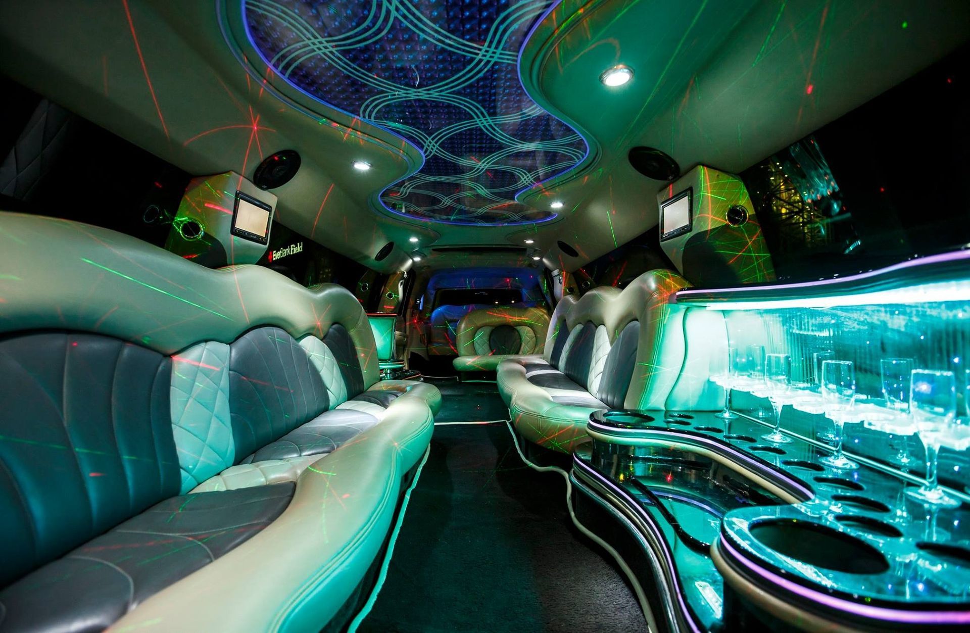Lavish limo interior with teal LED lighting, white leather seats, and mirrored ceiling accents