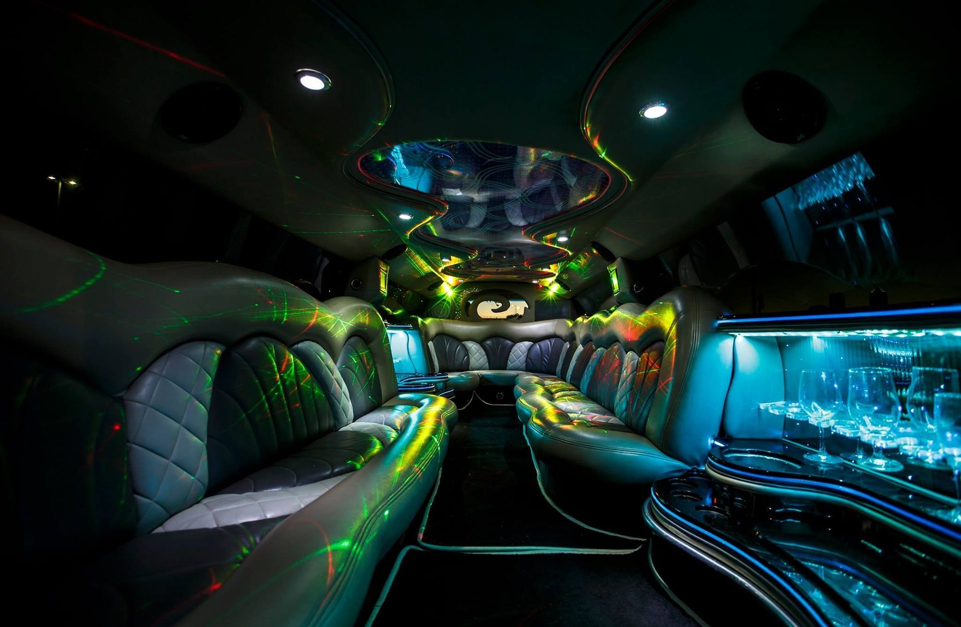Luxury limousine interior with neon lights, black leather seating, and blue-lit aquarium-style side panel