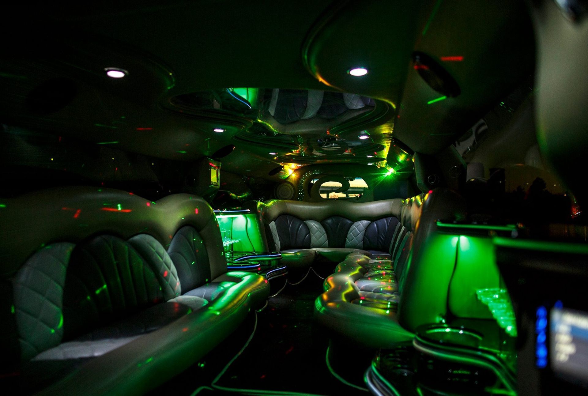 Futuristic limo interior with black leather seats and neon green lighting.