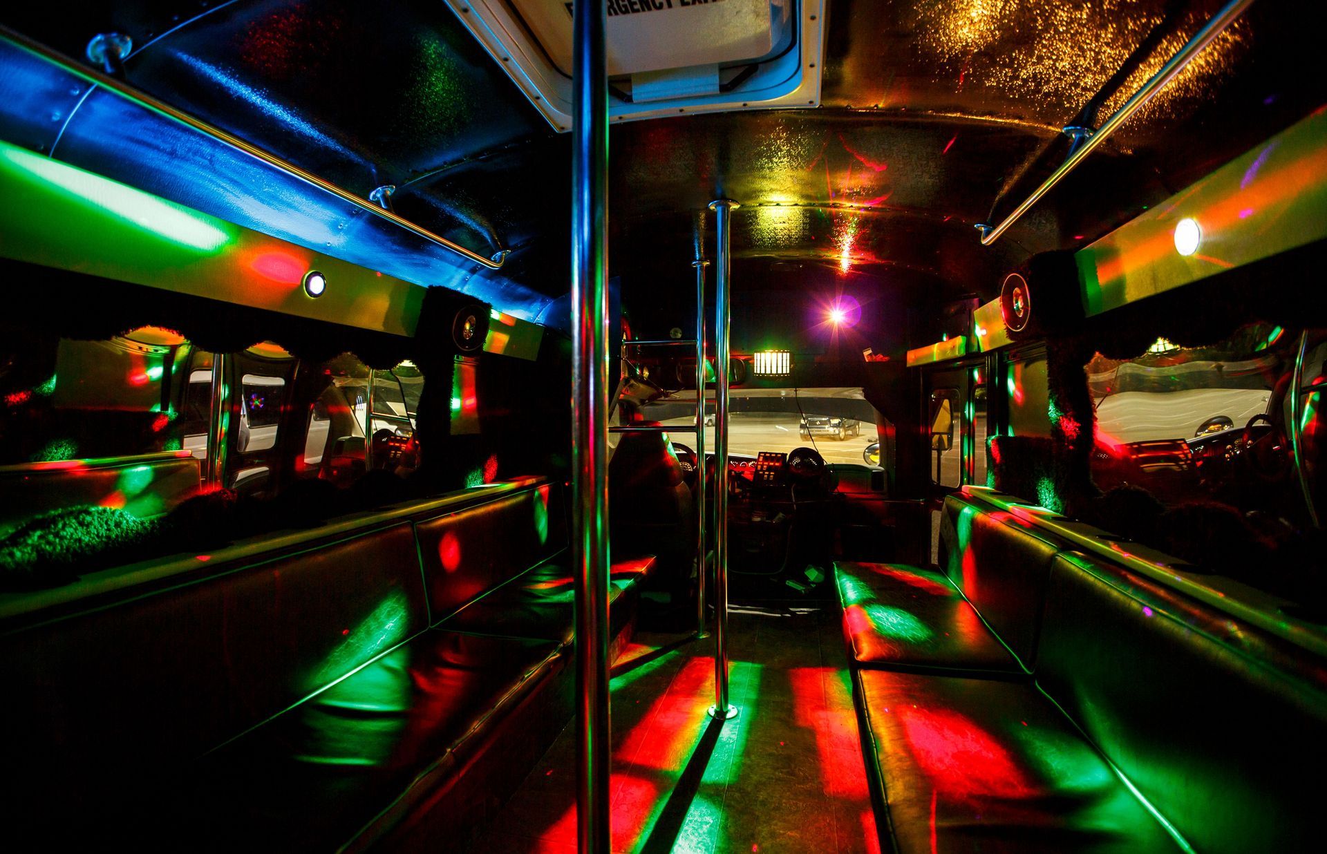Neon-lit bus interior with colorful reflections on chrome poles and seats at night